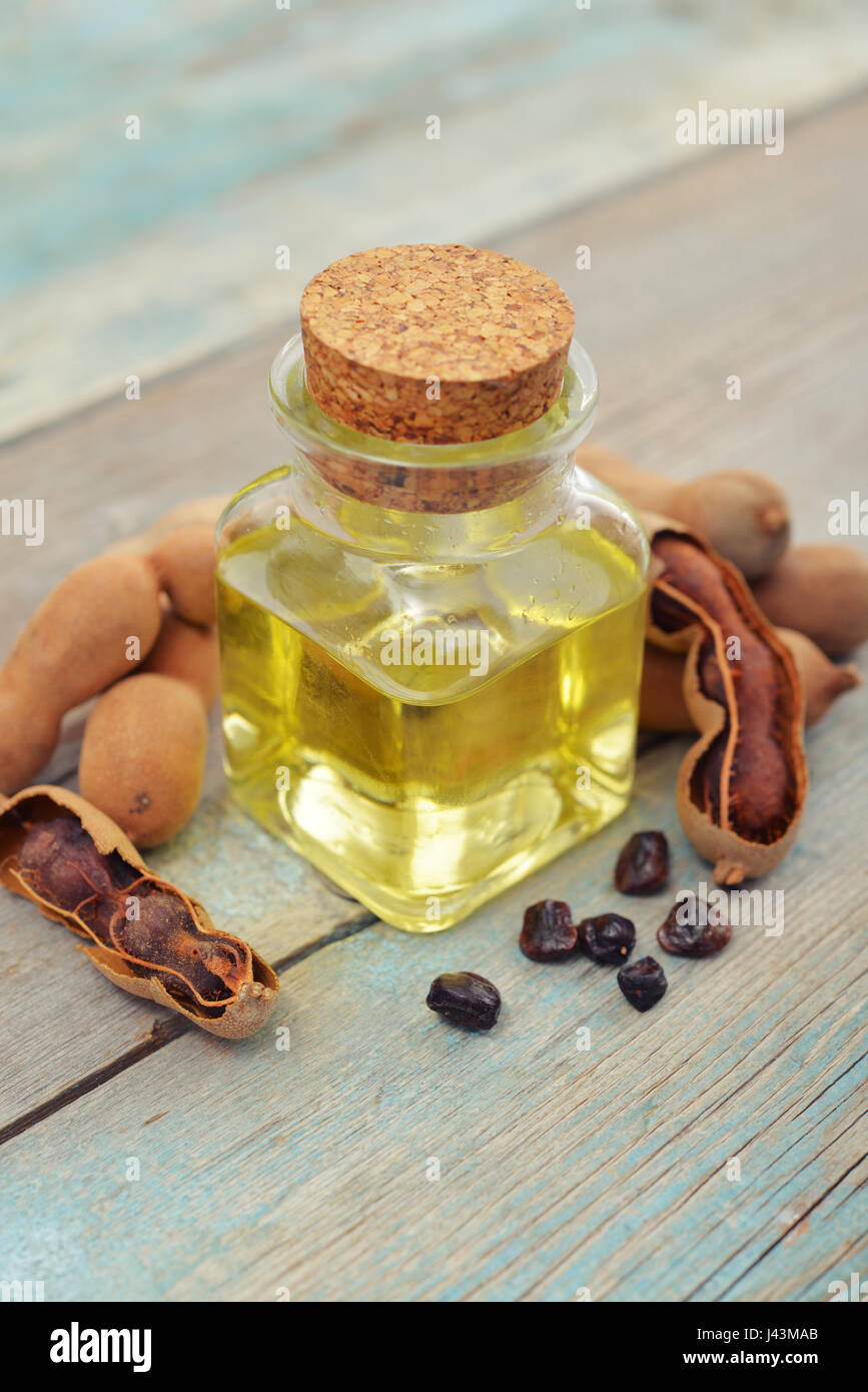Essenziale olio di tamarindo con cialde di tamarindo sul vecchio sfondo di legno Foto Stock