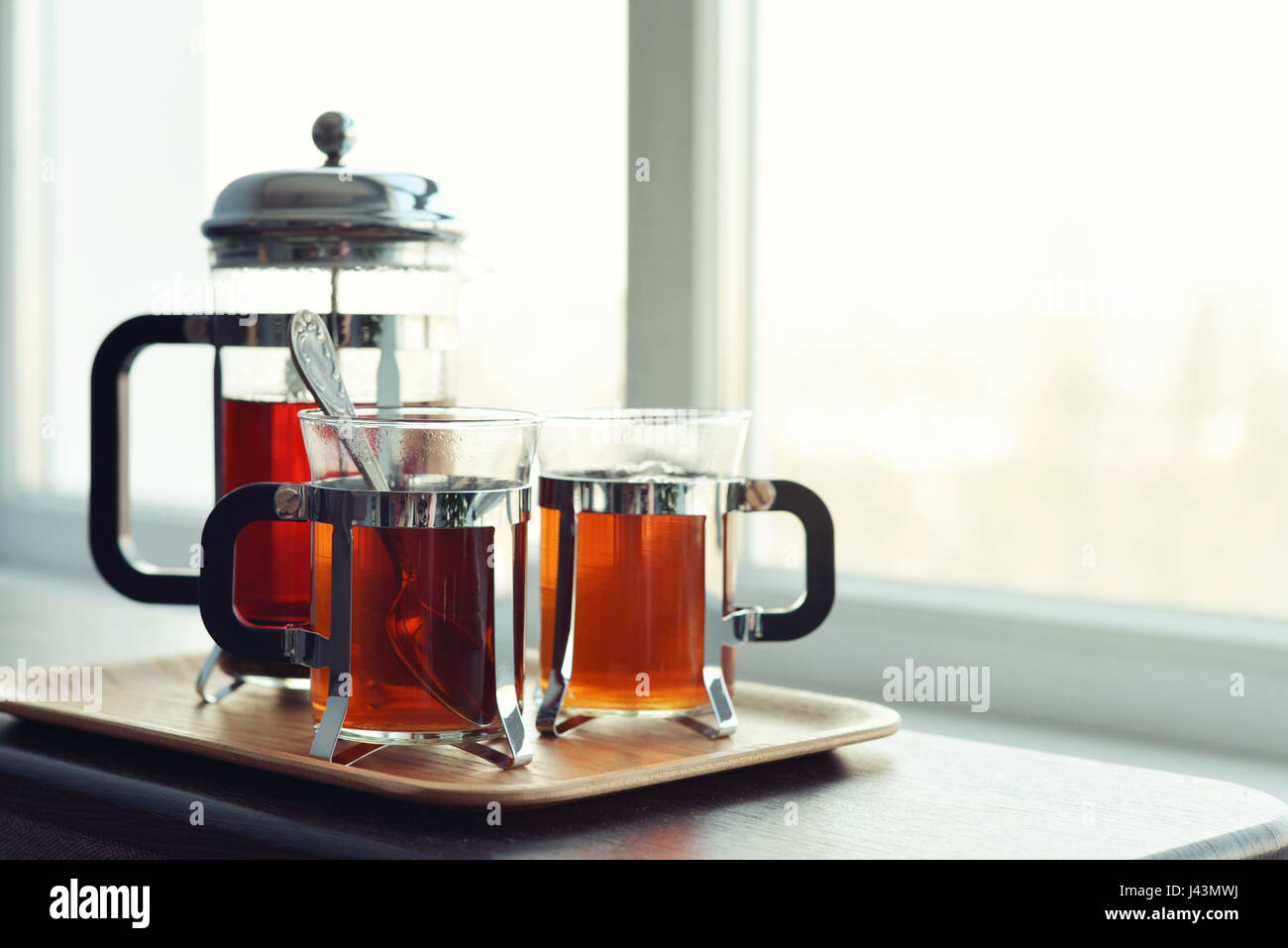 Tazze di tè con french press e limone sul divano nel soggiorno closeup. Foto Stock