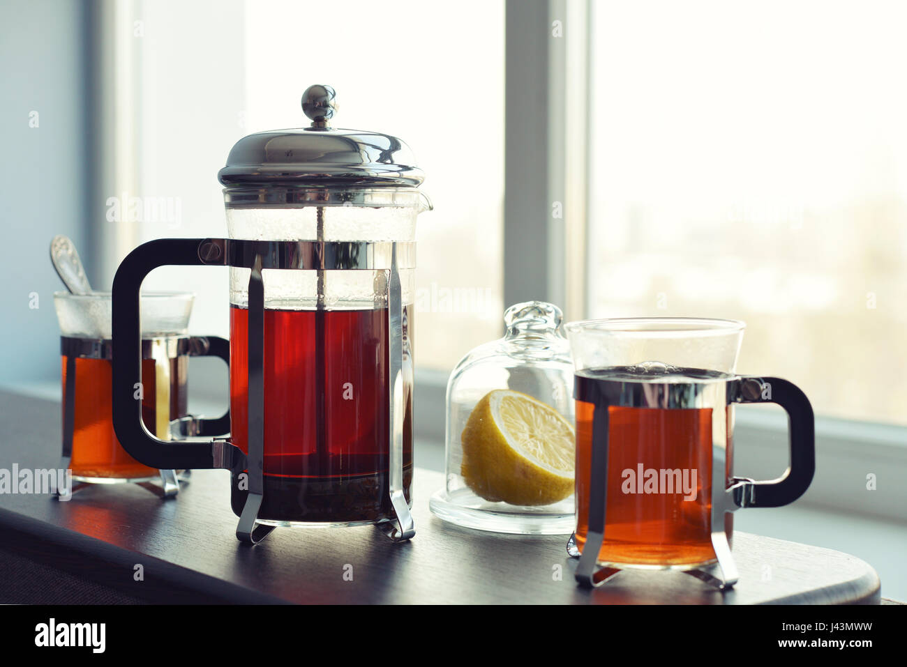 Tazze di tè con french press e limone sul divano nel soggiorno closeup. Foto Stock