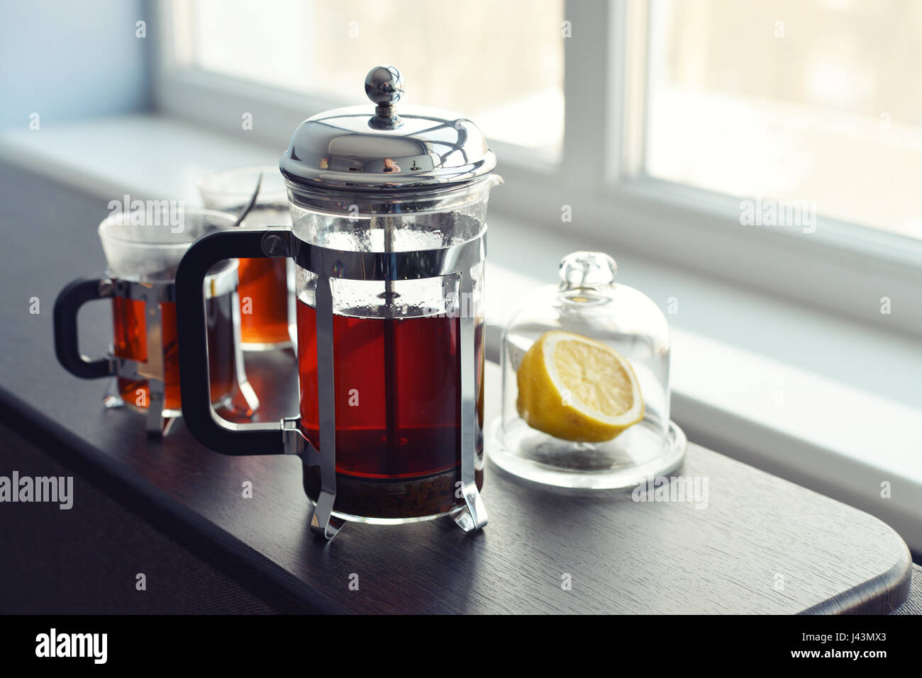 Tazze di tè con french press e limone sul divano nel soggiorno closeup. Foto Stock
