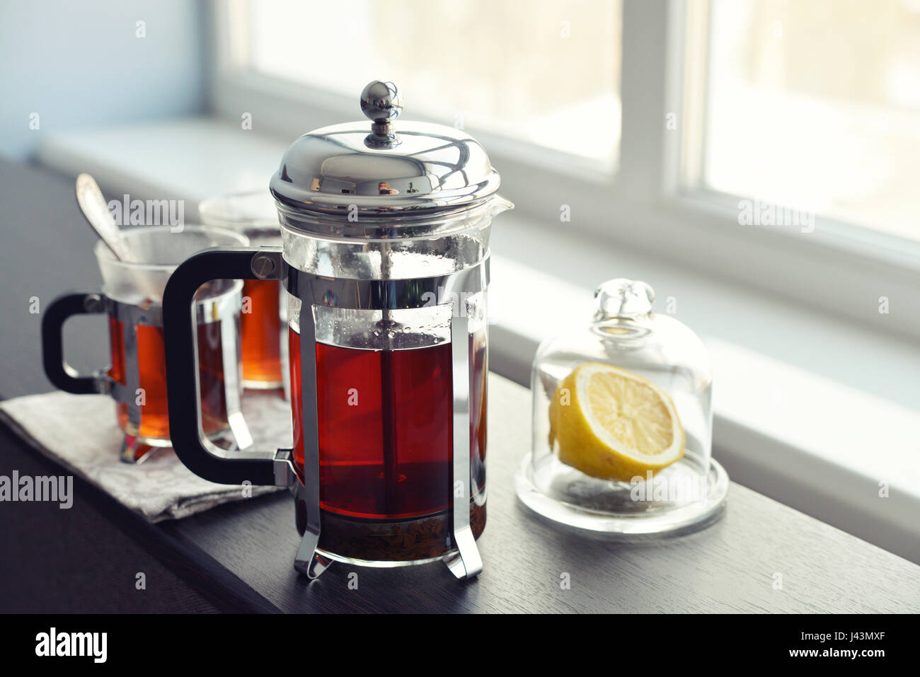 Tazze di tè con french press e limone sul divano nel soggiorno closeup. Foto Stock