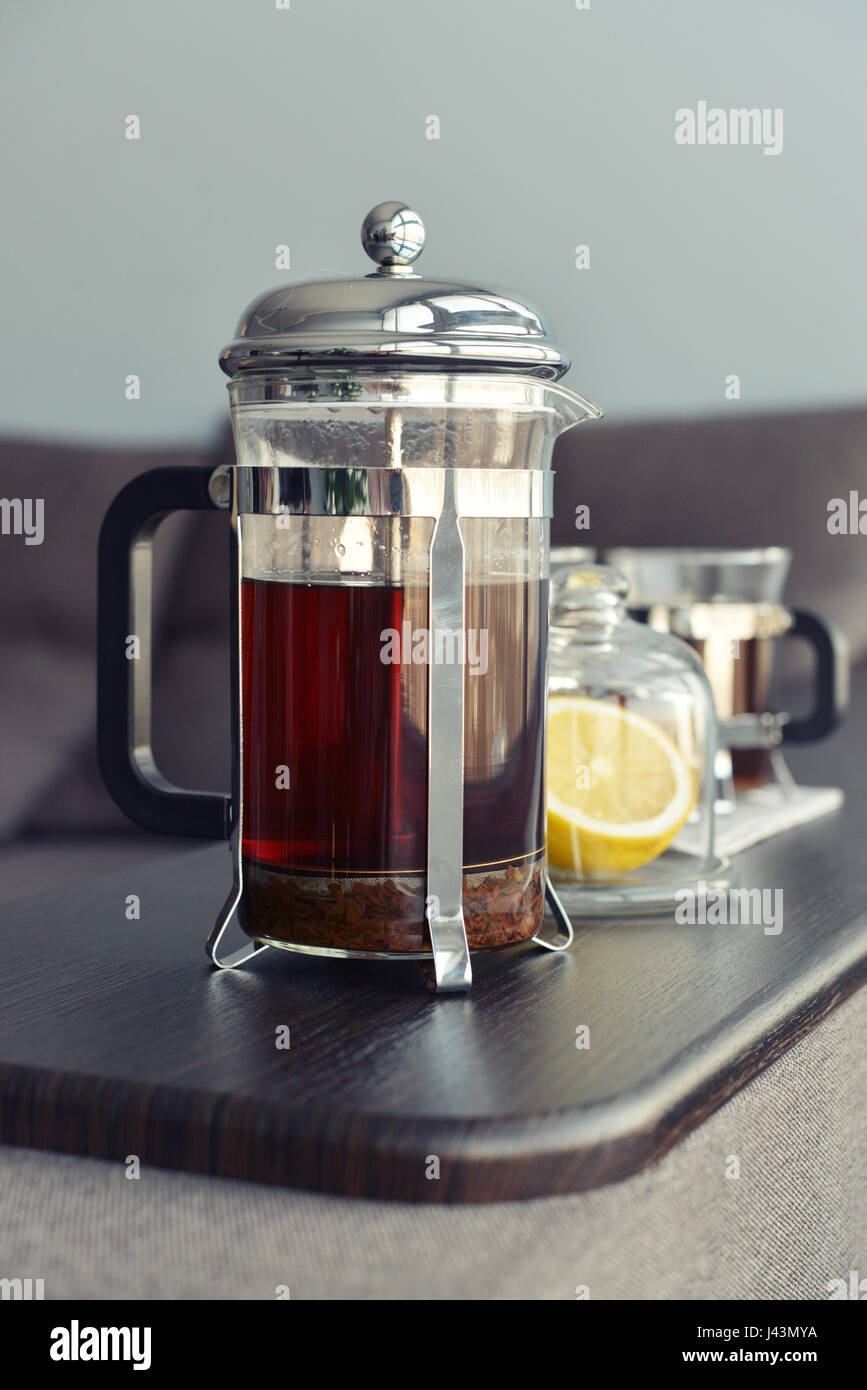 Tazze di tè con french press e limone sul divano nel soggiorno closeup. Foto Stock