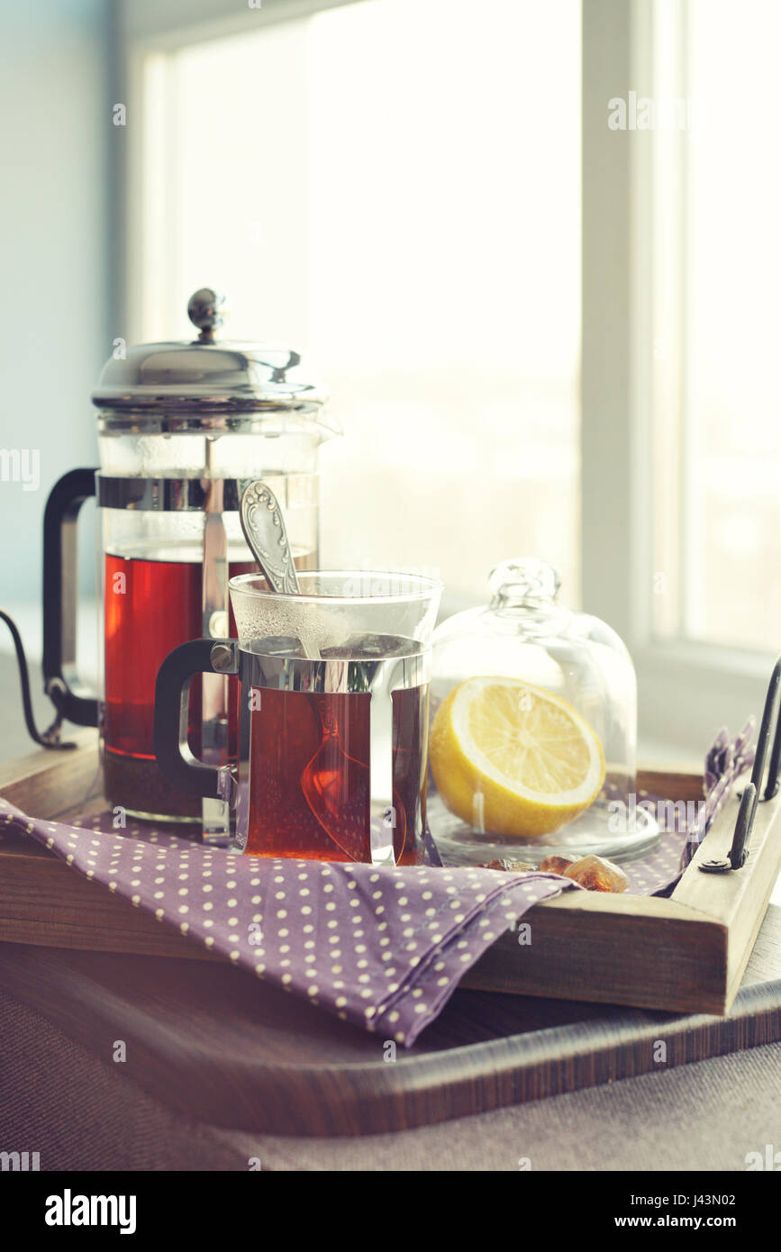 Tazze di tè con french press e limone sul divano nel soggiorno closeup. Foto Stock