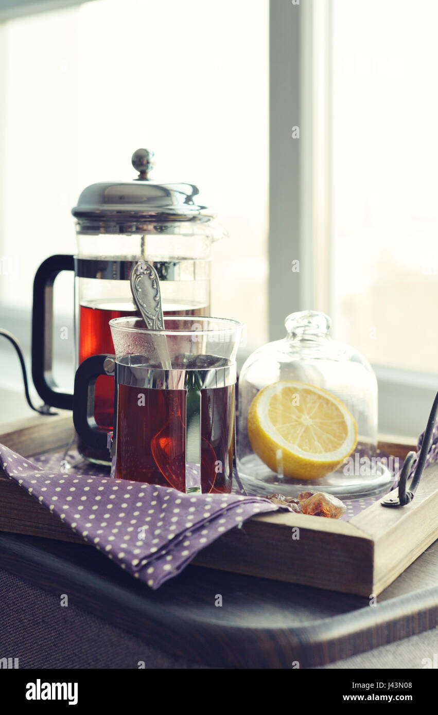 Tazze di tè con french press e limone sul divano nel soggiorno closeup. Foto Stock