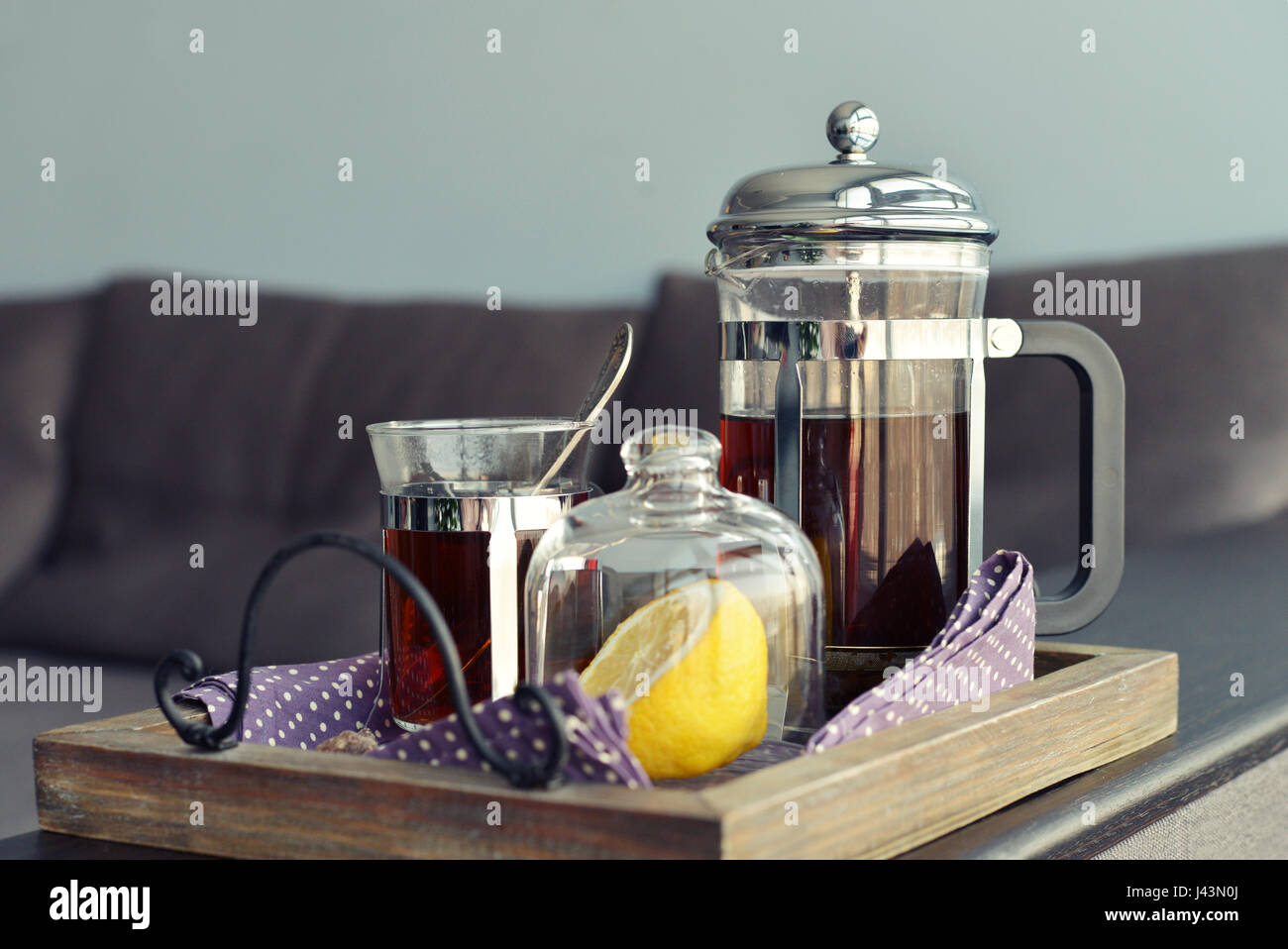 Tazze di tè con french press e limone sul divano nel soggiorno closeup. Foto Stock