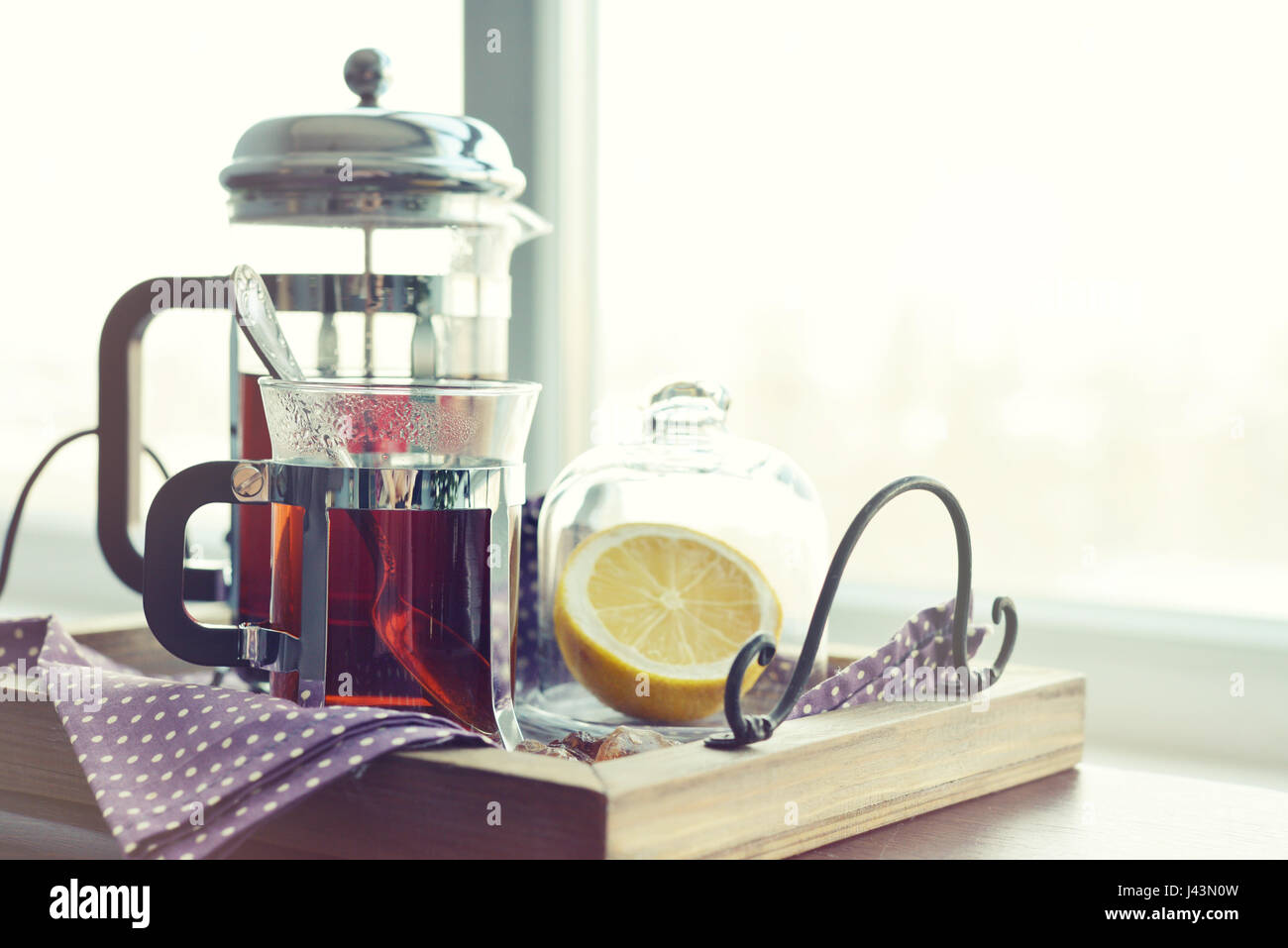 Tazze di tè con french press e limone sul divano nel soggiorno closeup. Foto Stock