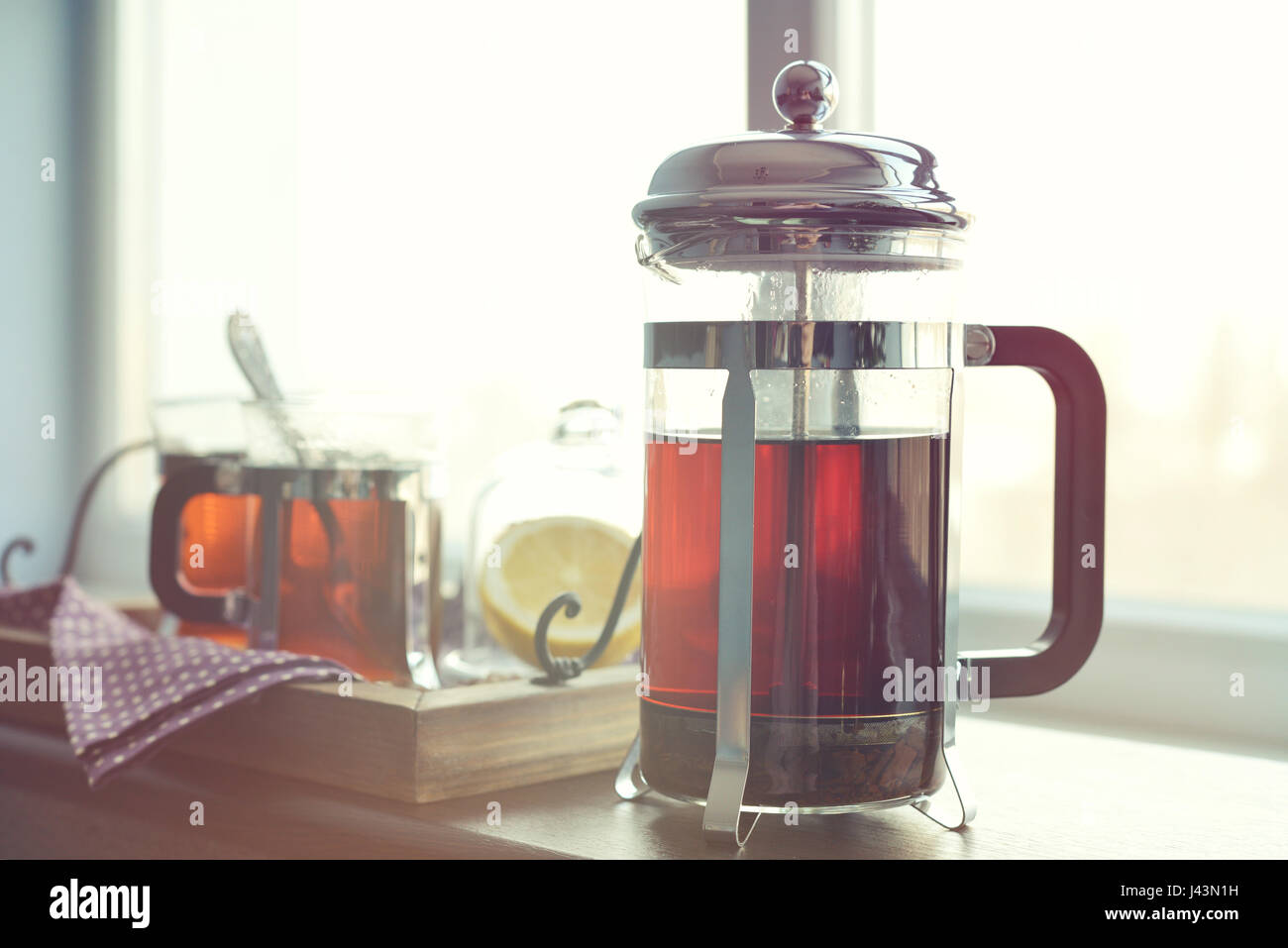 Tazze di tè con french press e limone sul divano nel soggiorno closeup. Foto Stock