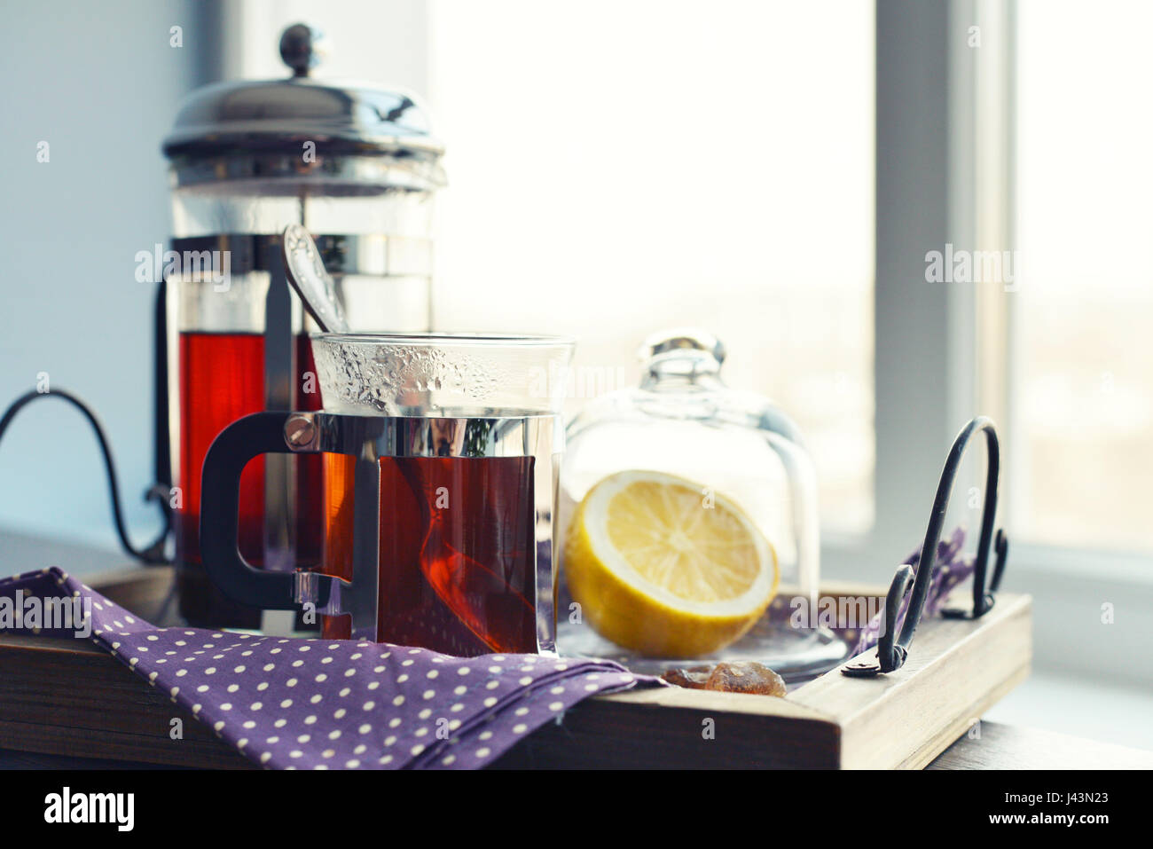 Tazze di tè con french press e limone sul divano nel soggiorno closeup. Foto Stock