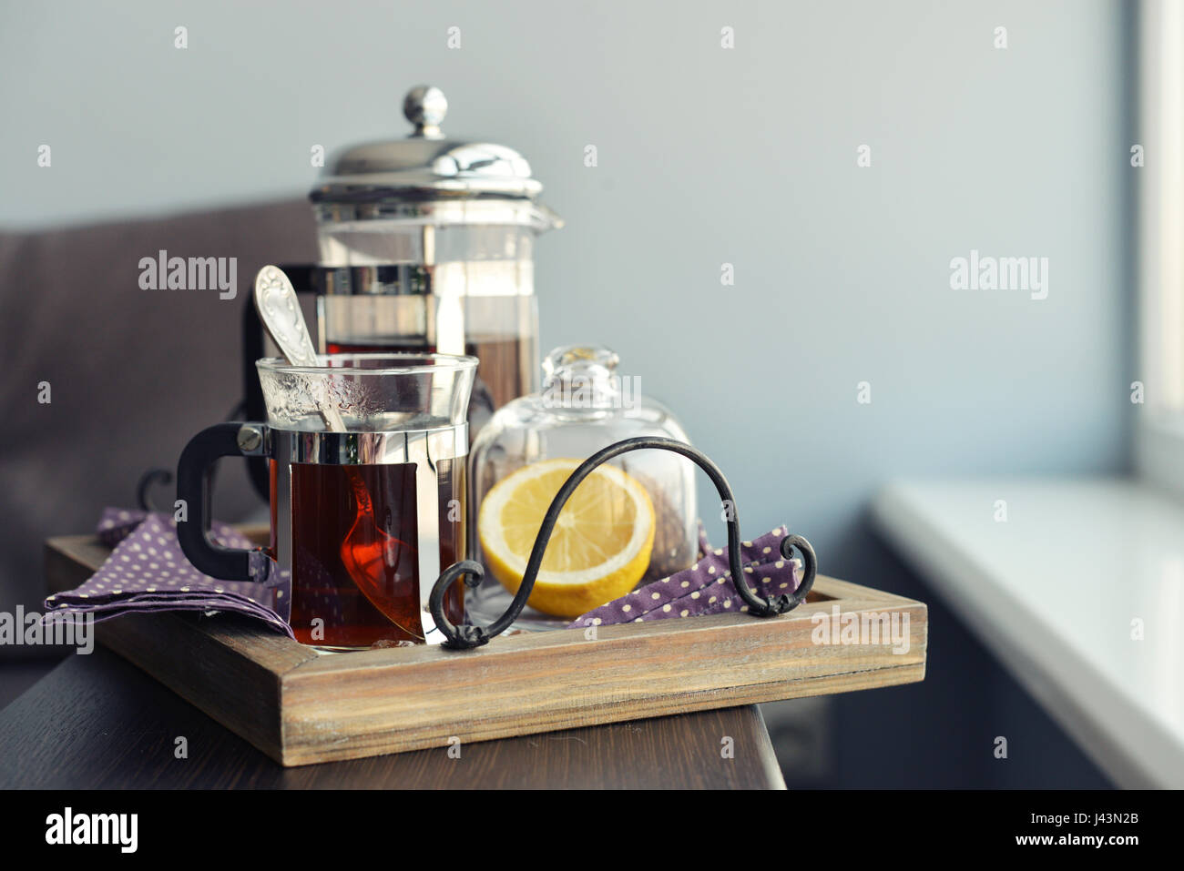 Tazze di tè con french press e limone sul divano nel soggiorno closeup. Foto Stock