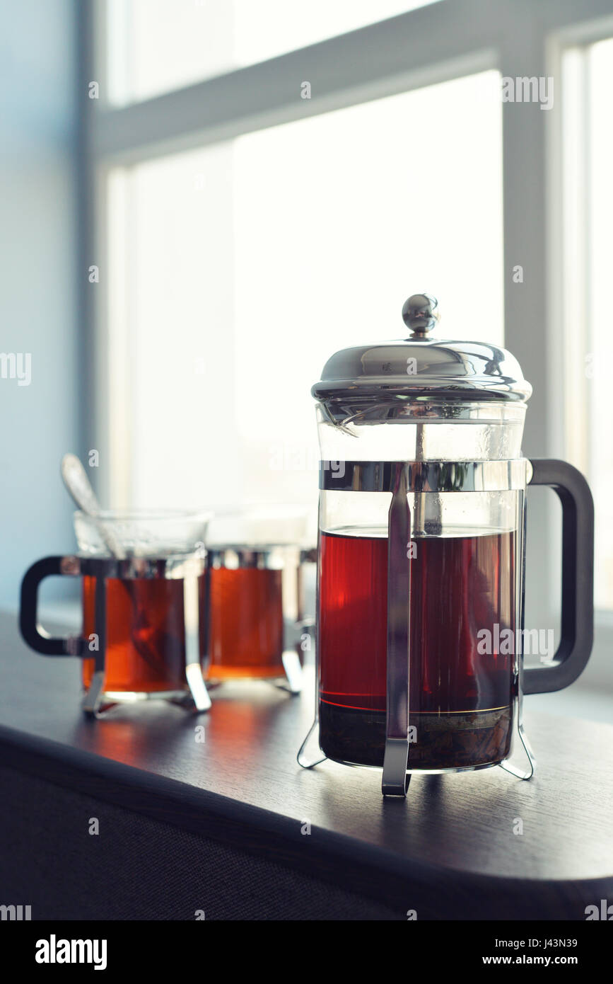 Tazze di tè con french press e limone sul divano nel soggiorno closeup. Foto Stock