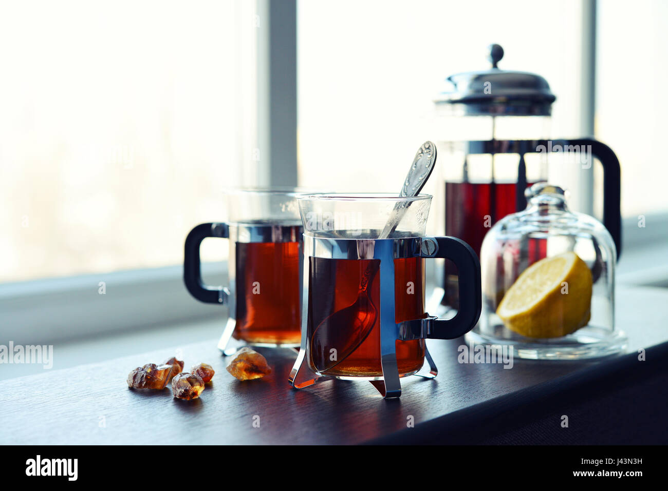 Tazze di tè con french press e limone sul divano nel soggiorno closeup. Foto Stock