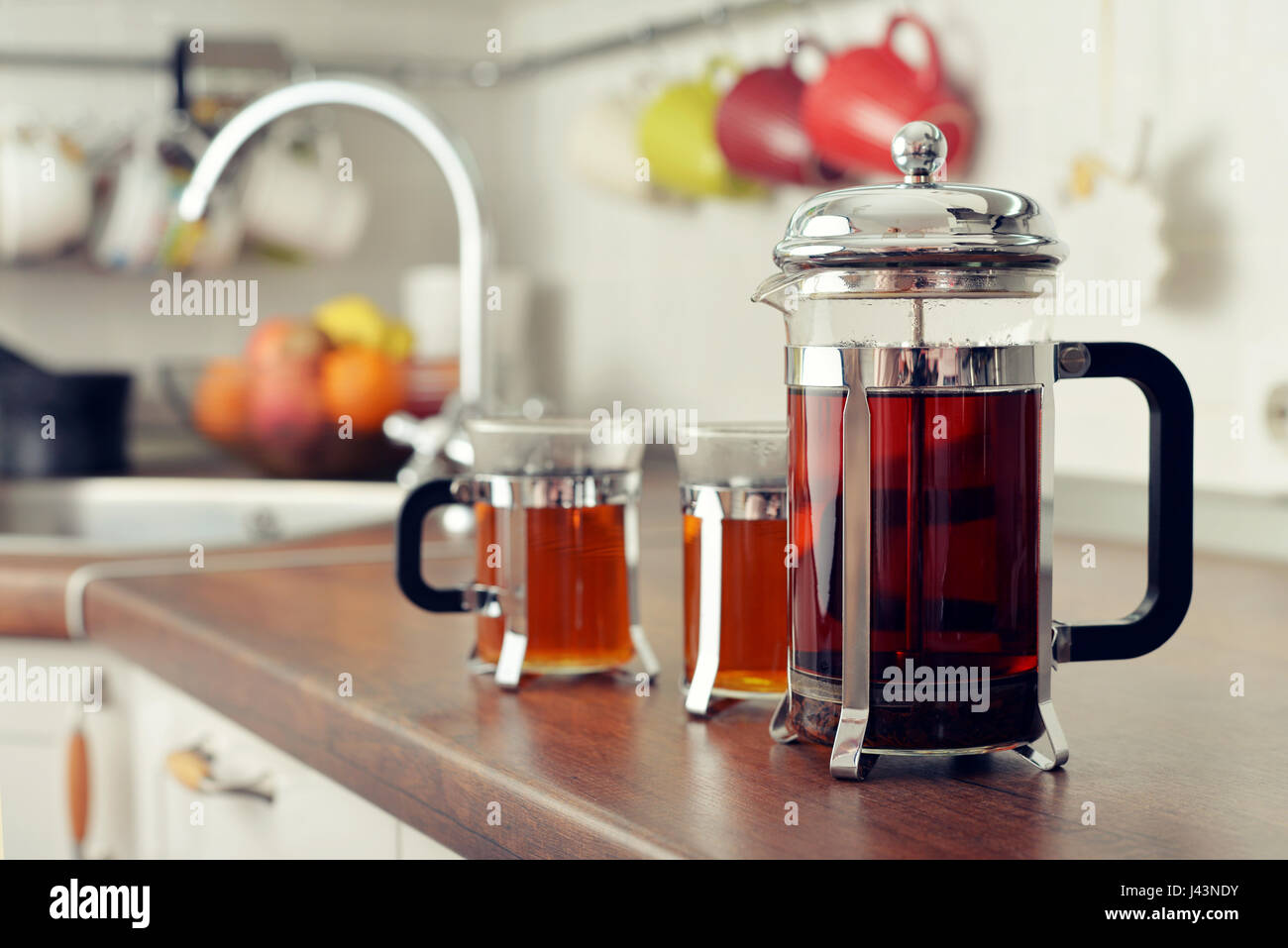 French press con tè e tazze sul piano cucina closeup Foto Stock