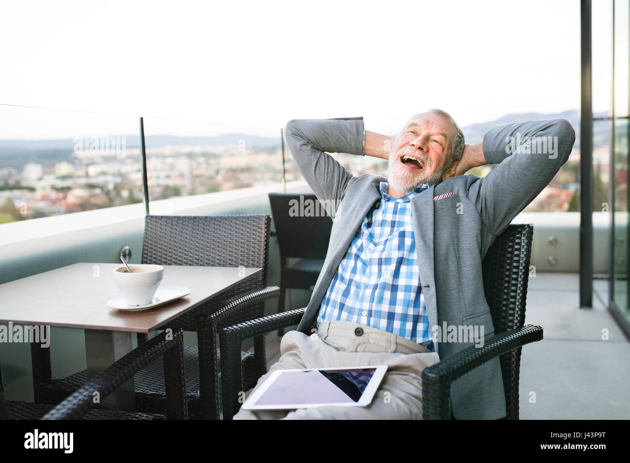 Imprenditore senior con una pastiglia nella caffetteria sul tetto Foto Stock