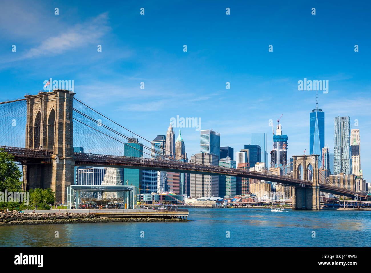 Luminoso panoramico vista Diurna del Ponte di Brooklyn con la parte inferiore della skyline di Manhattan in tutta l'East River sotto il cielo blu chiaro Foto Stock