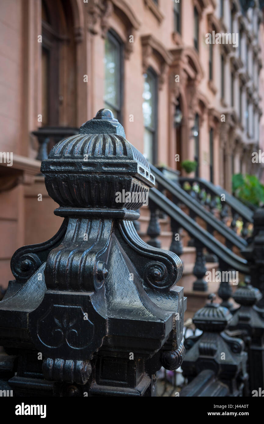 In prossimità di una ringhiera decorativo su un chinarsi davanti a una fila di tradizionali case di arenaria su un blocco storico di Brooklyn, a New York City Foto Stock
