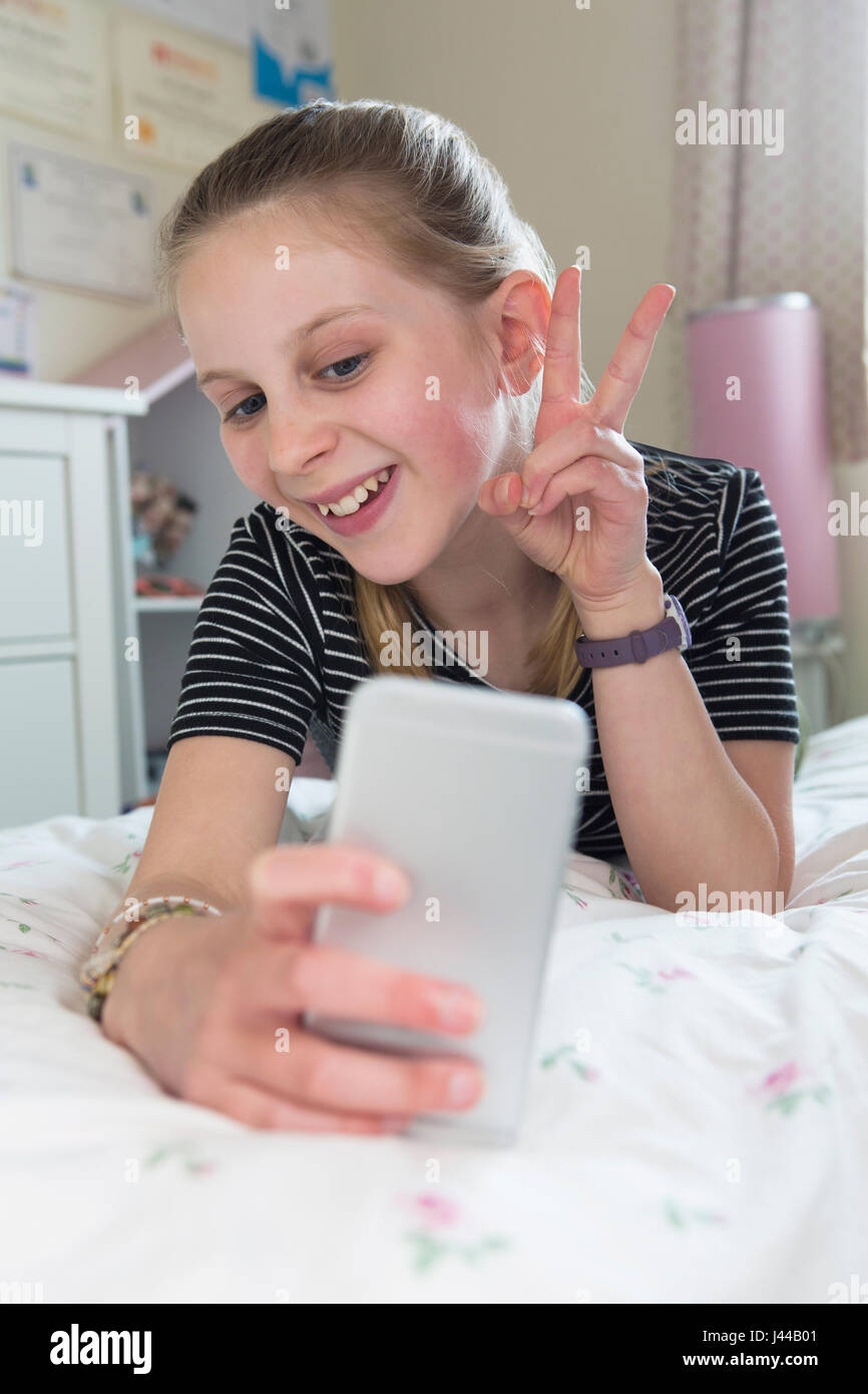 Giovane ragazza in posa per Selfie In camera da letto Foto Stock