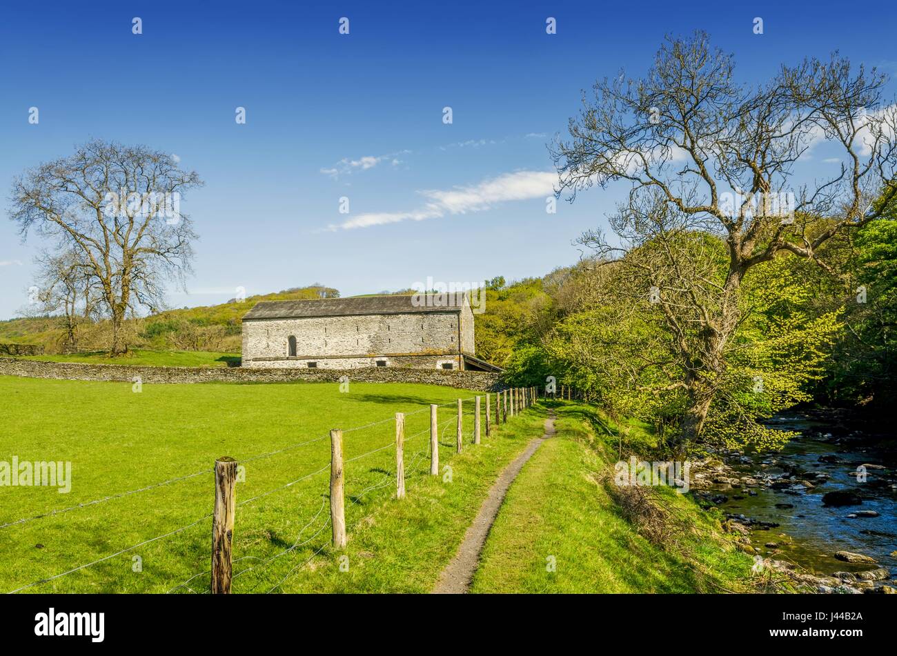 Un fienile isolato incastonate nel verde della campagna inglese e da un sentiero che costeggia il fiume. Foto Stock