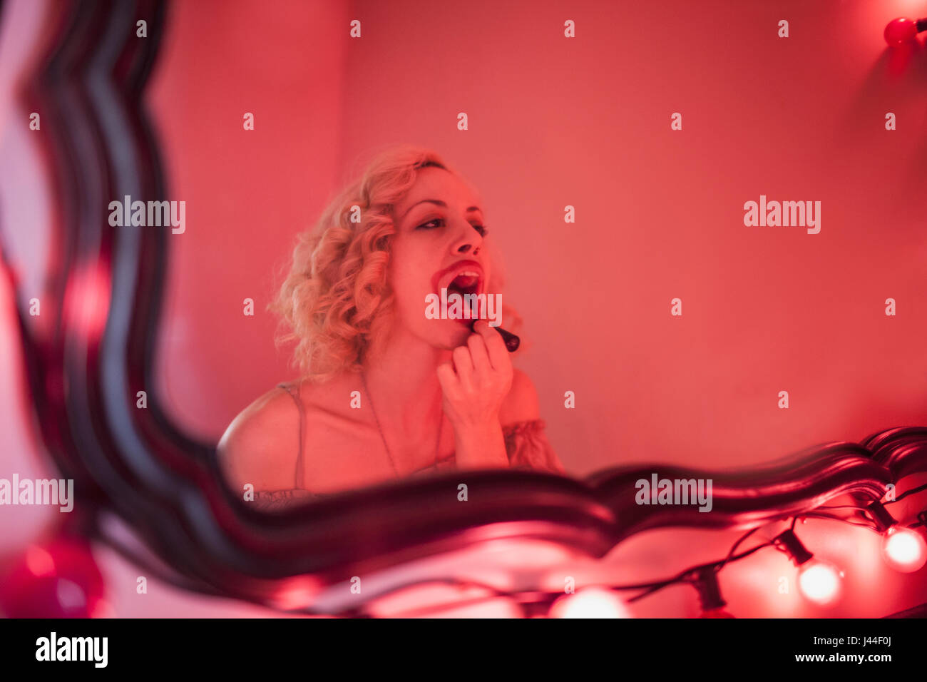 Una giovane donna rossetto in uno specchio. Foto Stock