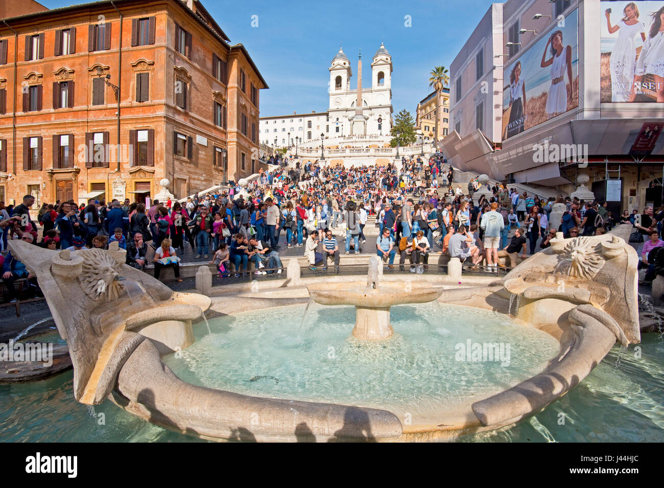 Scalinata di piazza di Spagna a Roma con i turisti in una giornata di sole con cielo blu chiesa di Trinità dei Monti sullo sfondo e la fontana del brutto barca in primo piano. Foto Stock