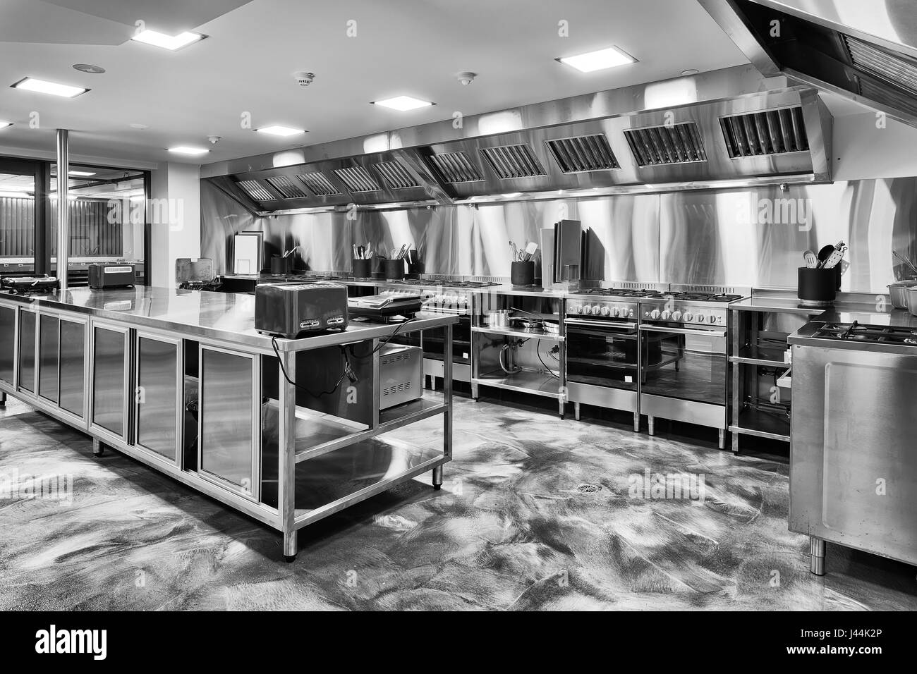 Moderno nuovo di zecca cucina completamente attrezzata con forni a gas, utensili da cottura Piani tavolo e appliences in bianco e nero. Foto Stock