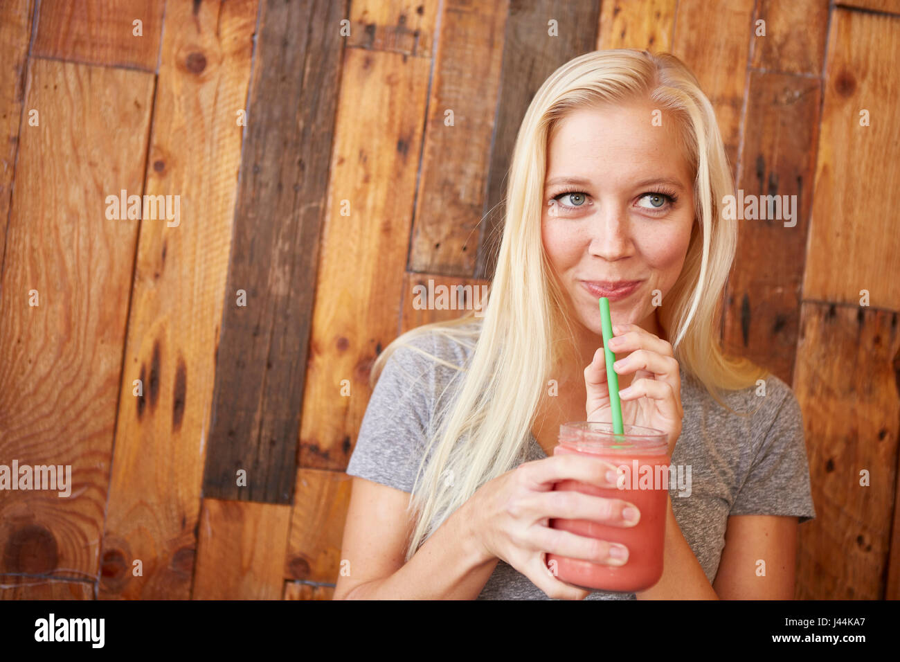 Felice sano giovane donna bere appena pressato succo in un cafe Foto Stock