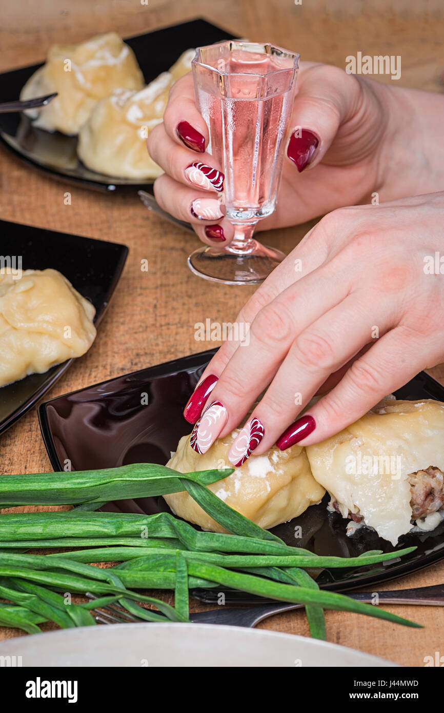 La mano femminile con belle manicure mantiene un colpo di vetro con vodka Foto Stock