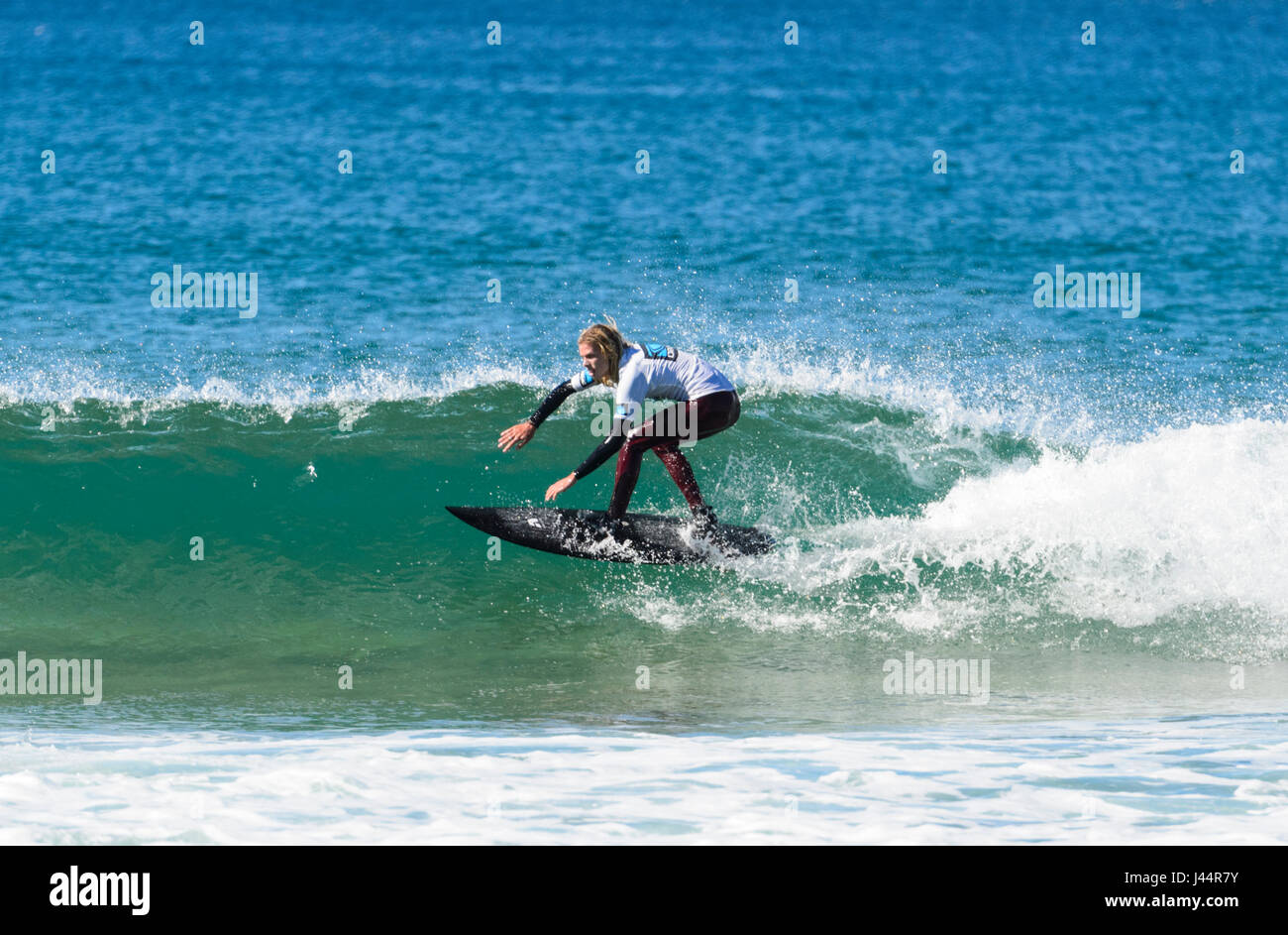 Giovane maschio con lunghi capelli biondi competere nel Werri Slash gara di surf, Gerringong, Nuovo Galles del Sud, NSW, Australia Foto Stock