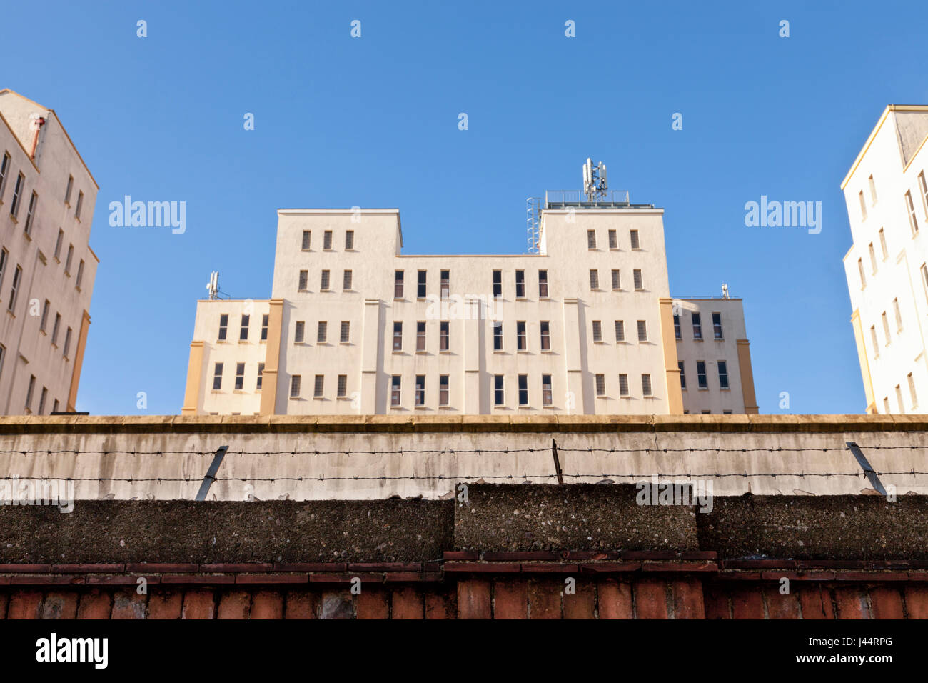 1930s degli edifici adibiti a magazzino dietro un muro di sicurezza e rabboccato con vetro e filo spinato. Originariamente utilizzato da John Player e figli, Nottingham, Inghilterra, Regno Unito Foto Stock
