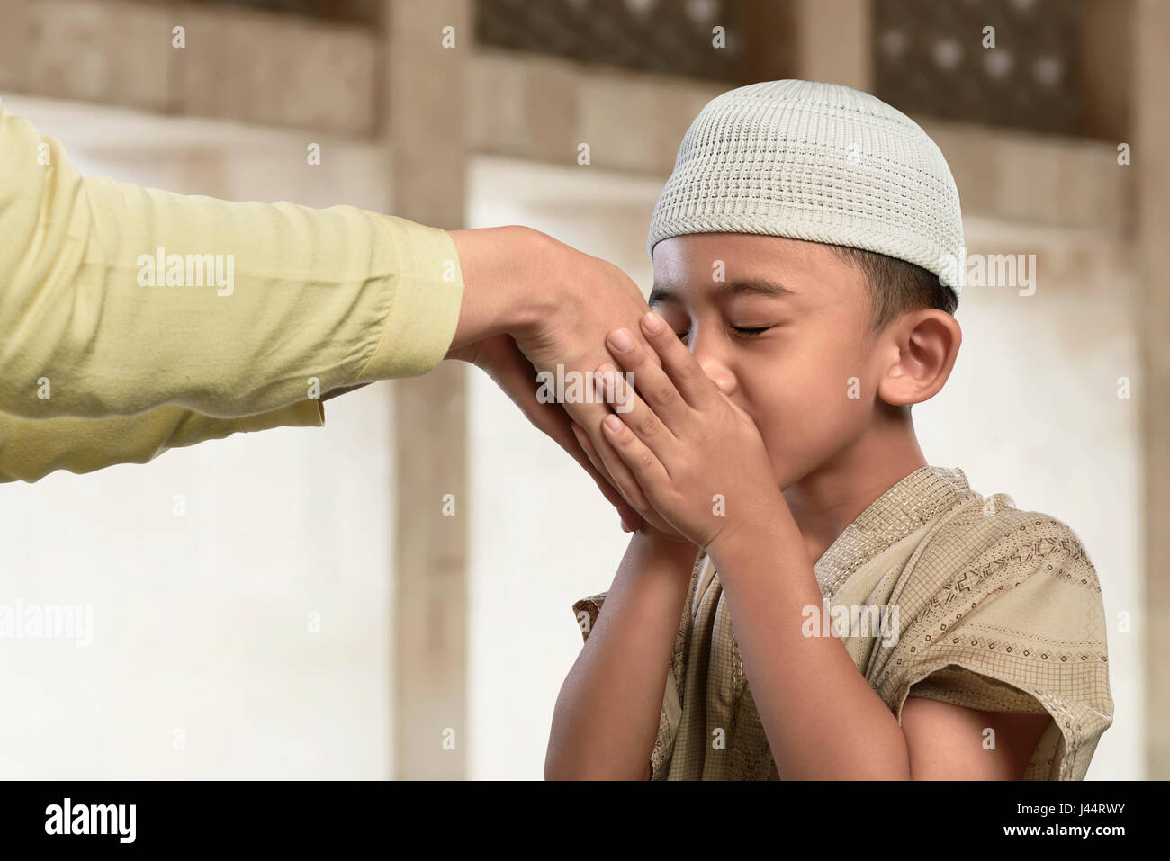 Musulmani asiatici bambino baciare una mano da un antico popolo nella moschea Foto Stock