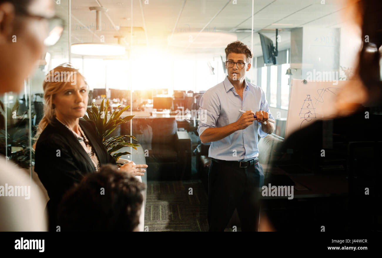 Imprenditore maturo fare una presentazione su un flip-chart e discutere. Il team di Business strategia durante la riunione in ufficio moderno. Foto Stock