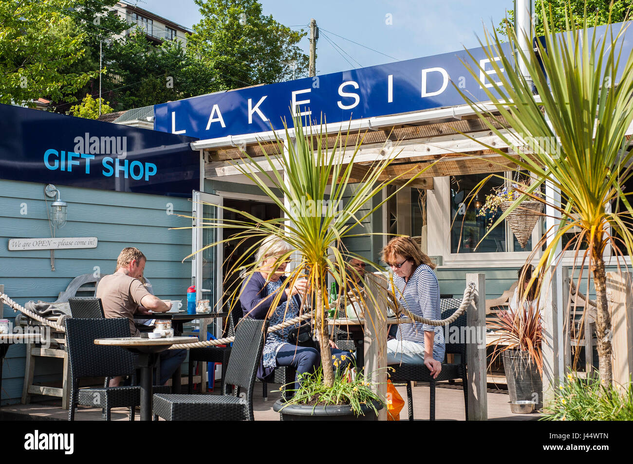 I clienti seduti in un'area esterna di un cafe persone prendendo una pausa rilassante sunshine Sunny pasti al fresco segno Segni ristorante sul lago Foto Stock