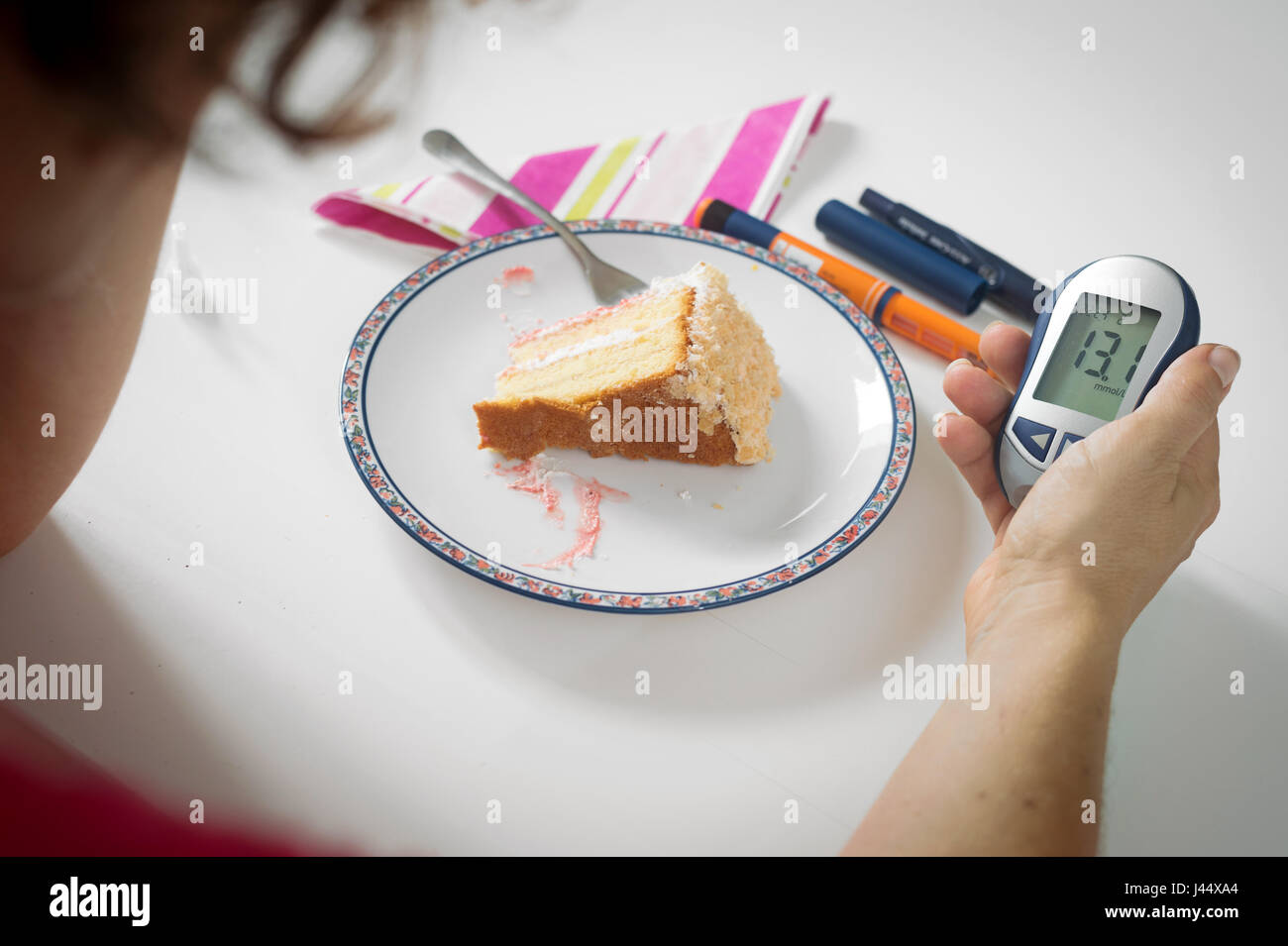 Femmina lato mantenendo i livelli di zucchero nel sangue metro vicino alla piastra di torta. Il diabete, ad alto livello di zucchero nel sangue, il moderno concetto di malattia. Foto Stock
