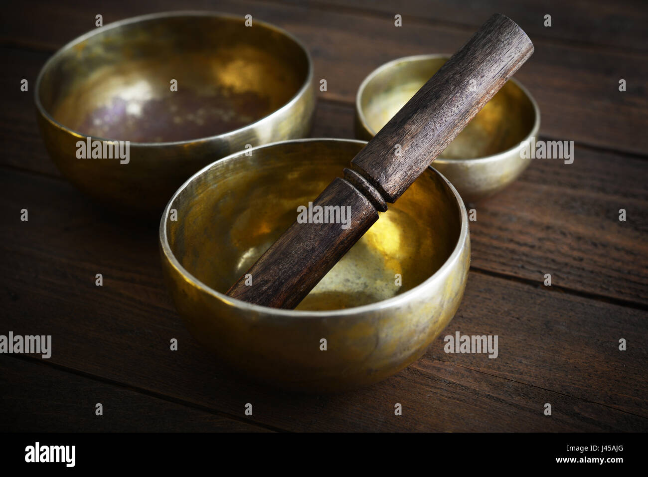 Il Tibetano handcrafted SINGING BOWLS con bastoni sullo sfondo di legno Foto Stock