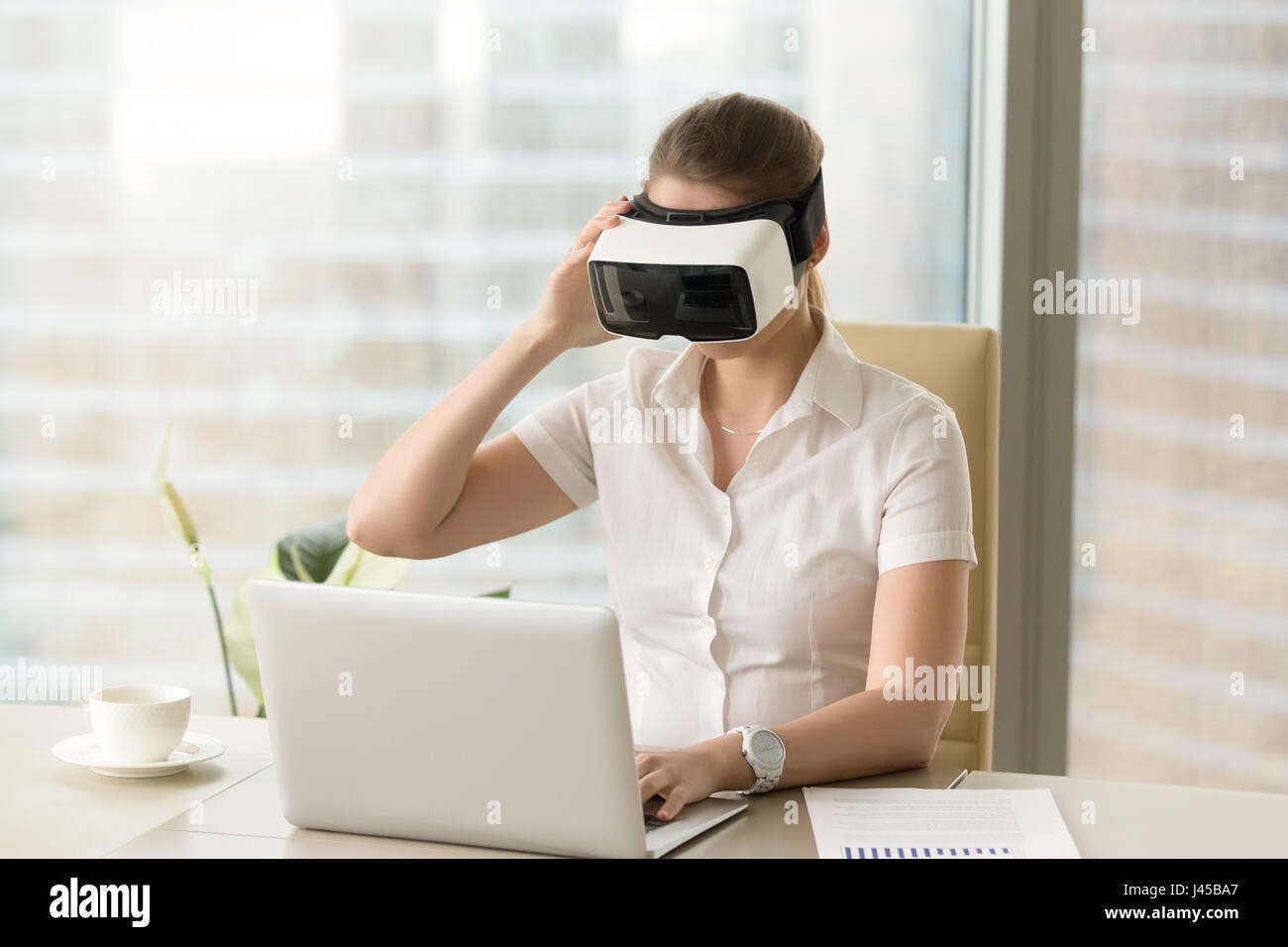 Imprenditrice sincronizza VR auricolare con laptop Foto Stock