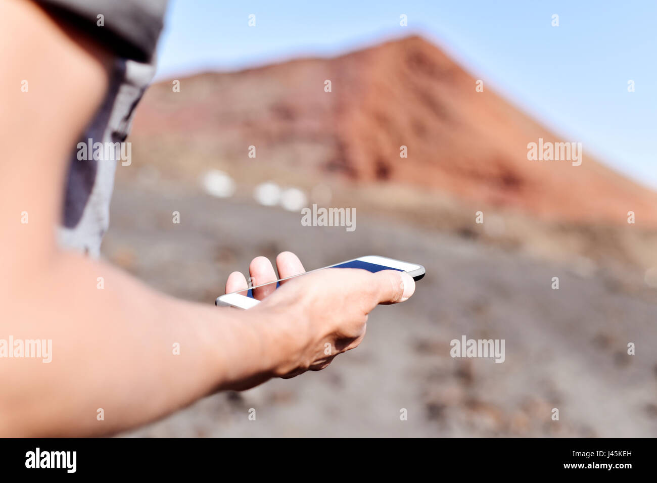 Primo piano di un giovane uomo caucasico utilizzando uno smartphone all'aperto, in montagna Foto Stock