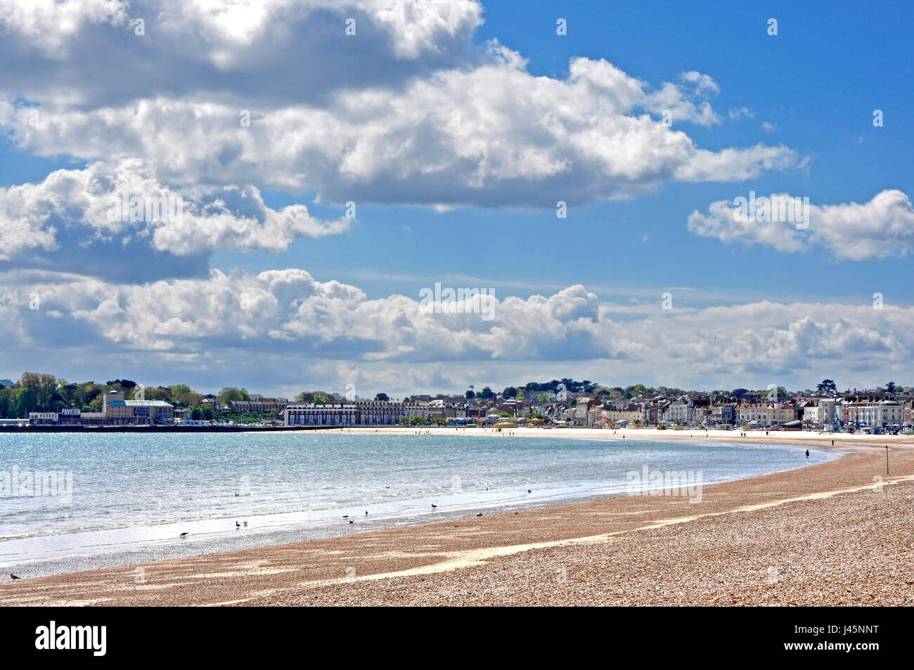 Spiaggia di Weymouth Dorset - vista panoramica di spazzamento di vista mare - città interessante al di là - inizio estate la luce del sole - il mare blu e il cloud chiazzata sky Foto Stock