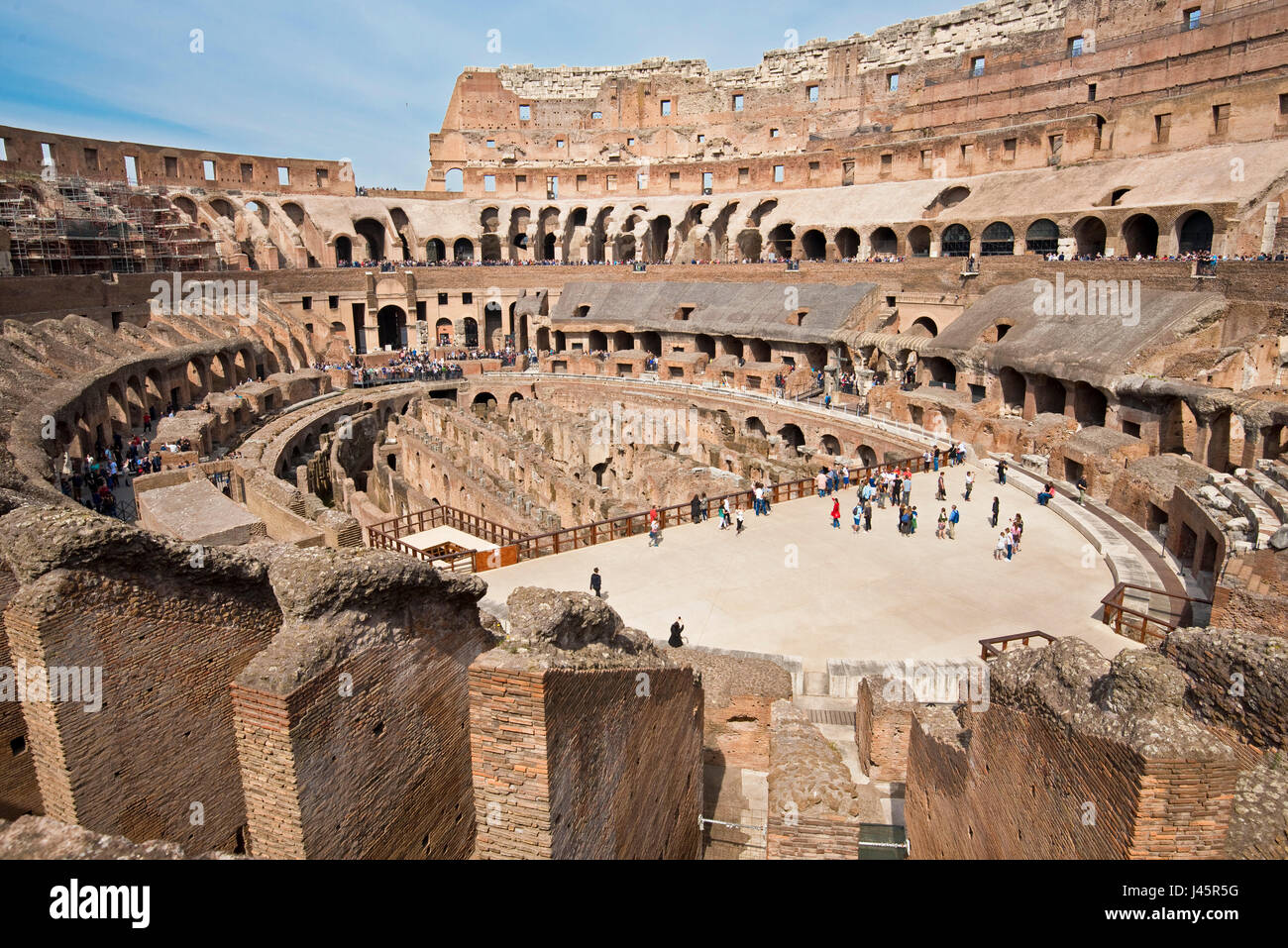 Un ampio angolo di vista interna dell'anfiteatro all'interno del Colosseo con i turisti i visitatori in una giornata di sole con cielo blu preso dal livello medio 2. Foto Stock