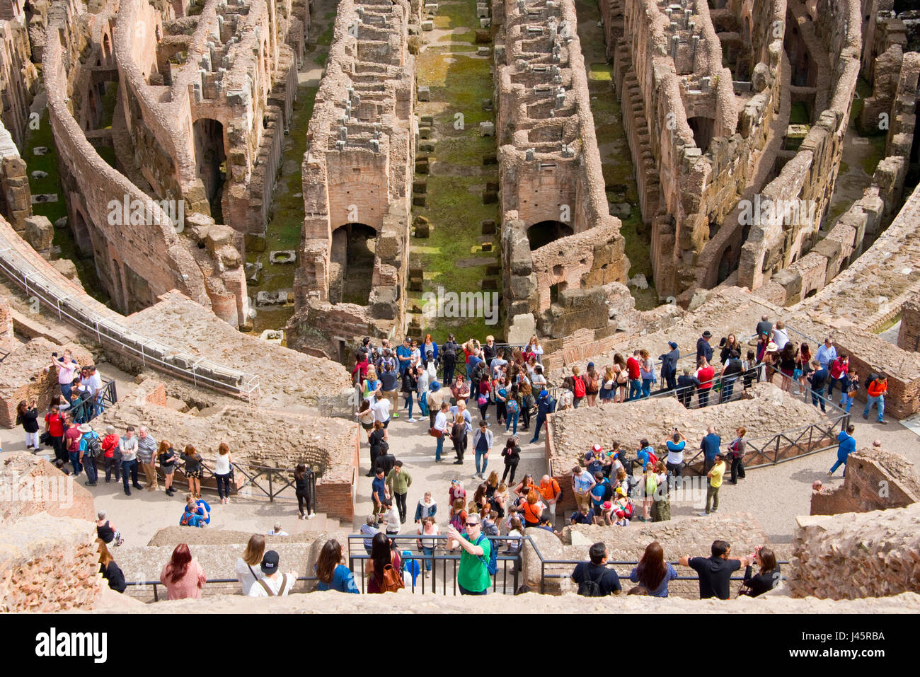 Un' antenna prospettiva compressa vista interna dell'anfiteatro all'interno del Colosseo con i turisti i visitatori in una giornata di sole. Foto Stock