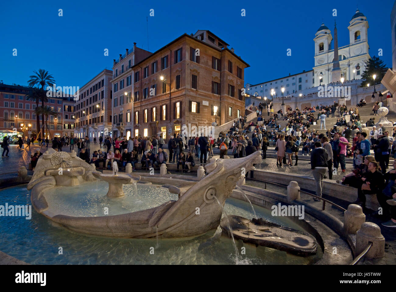 Scalinata di piazza di Spagna a Roma con i turisti e visitatori di sera e notte con la chiesa di Trinità dei Monti sullo sfondo e la fontana del brutto barca in primo piano. Foto Stock