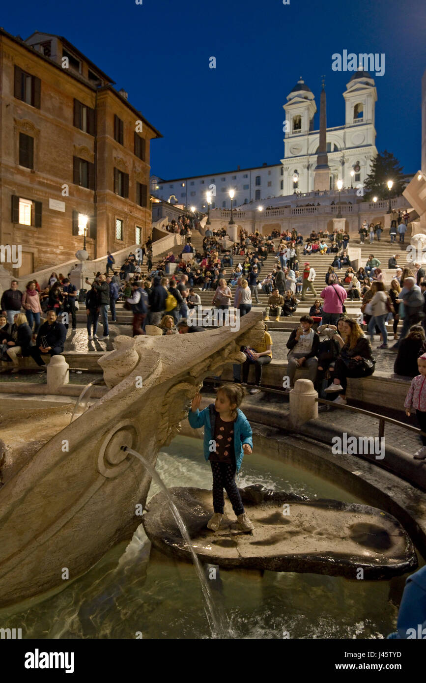 Scalinata di piazza di Spagna a Roma un turista in posa per una fotografia alla fontana del brutto barca la sera, la notte con la chiesa di Trinità dei Monti sullo sfondo. Foto Stock