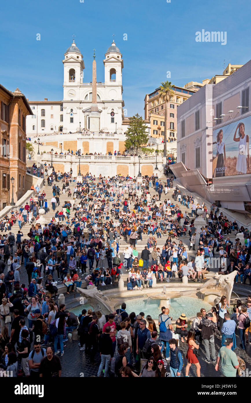 Scalinata di piazza di Spagna a Roma con la folla di turisti in una giornata di sole con cielo blu chiesa di Trinità dei Monti Fontana di sfondo del brutto barca in primo piano. Foto Stock