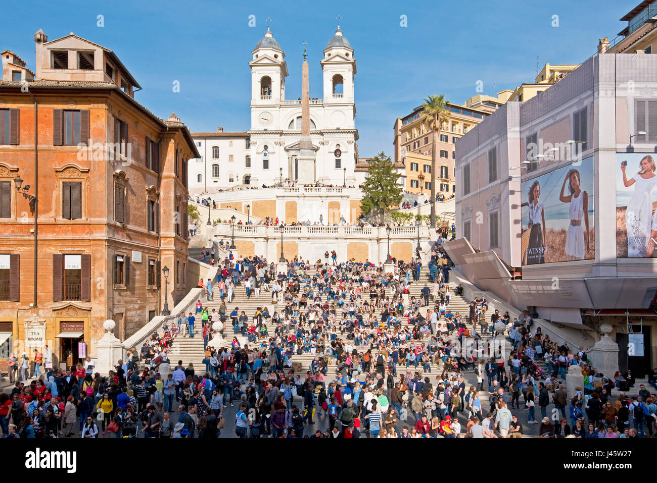Scalinata di piazza di Spagna a Roma con la folla di turisti e visitatori in una giornata di sole con cielo blu e la chiesa di Trinità dei Monti in background. Foto Stock