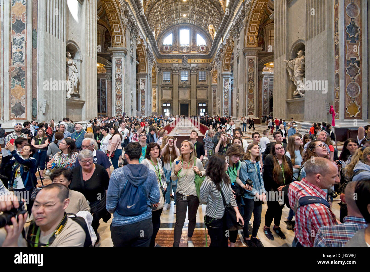 Un ampio angolo di vista interna all'interno della Basilica di San Pietro della principale alterare e la folla di turisti e visitatori. Foto Stock