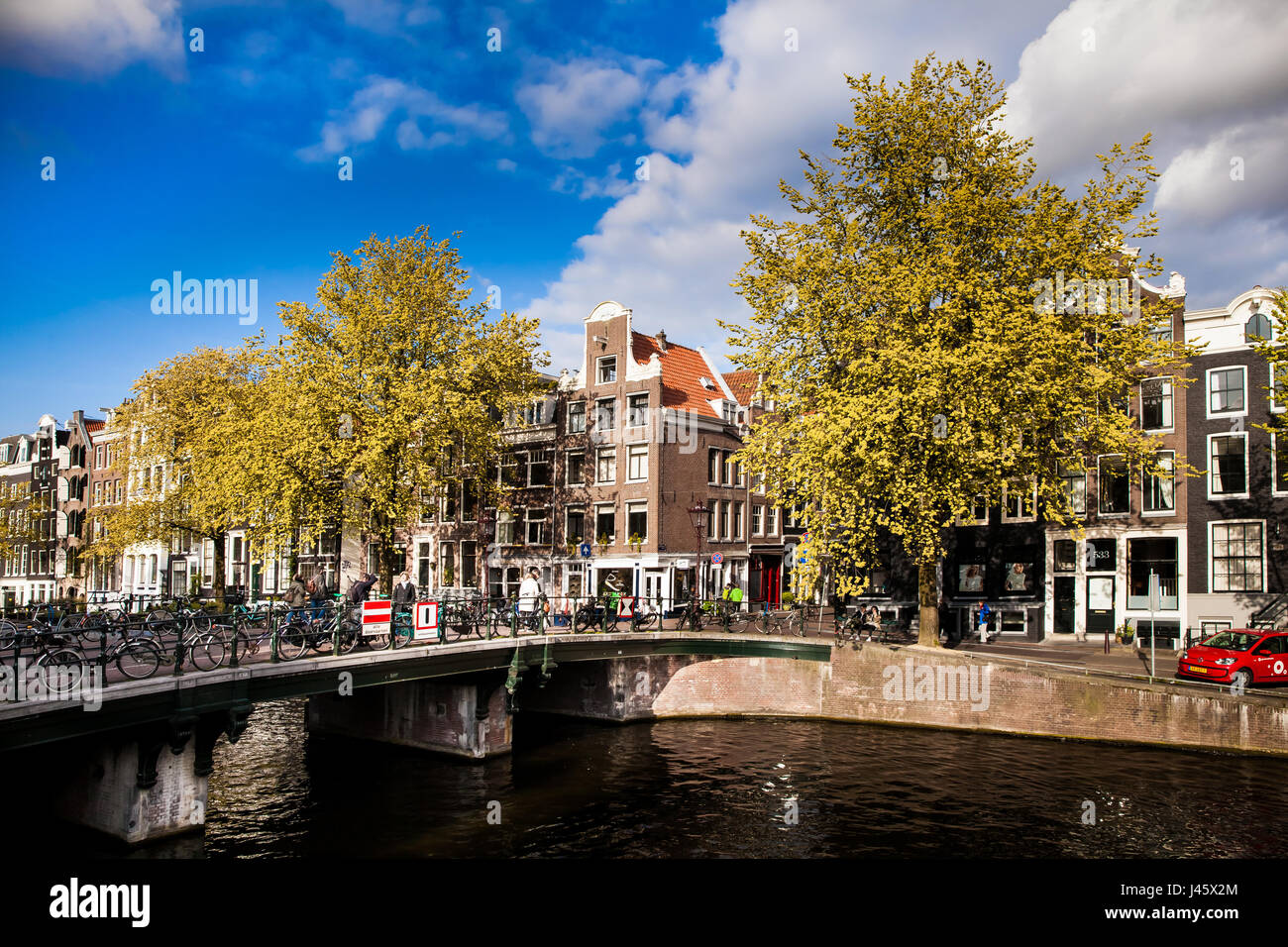 Soleggiata giornata di primavera in Amsterdam. Vista sul canale con case tradizionali e biciclette, Paesi Bassi Foto Stock