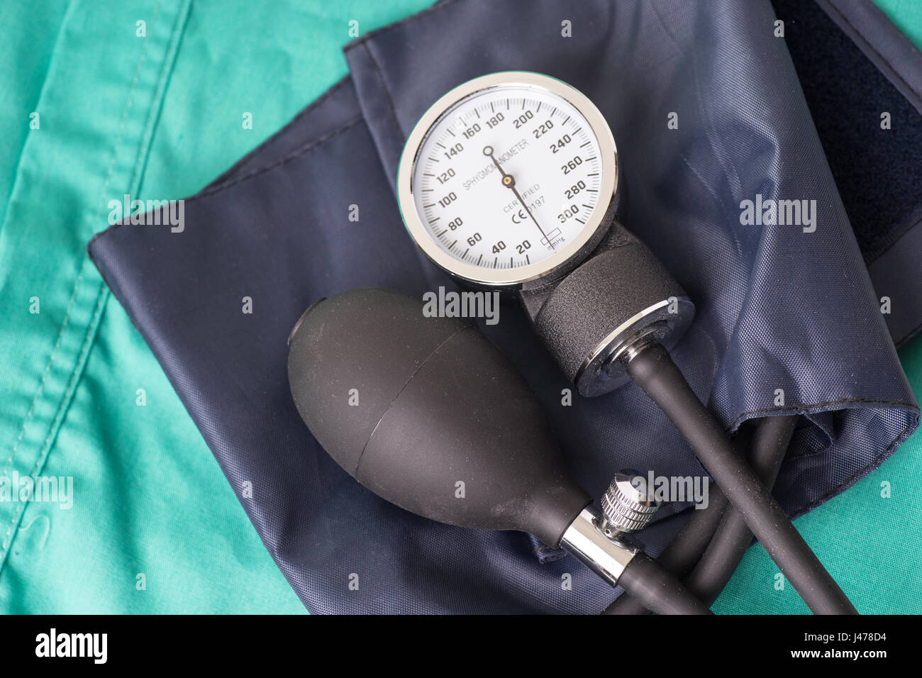 La pressione sanguigna dispositivo situato sull'ospedale sfondo verde. Lo sfondo può essere una parte di tessili di un medico o un infermiere uniforme di lavoro Foto Stock