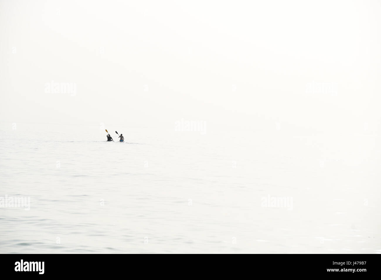 Chiave di alta immagine di due figure distanti canottaggio nell'oceano Foto Stock