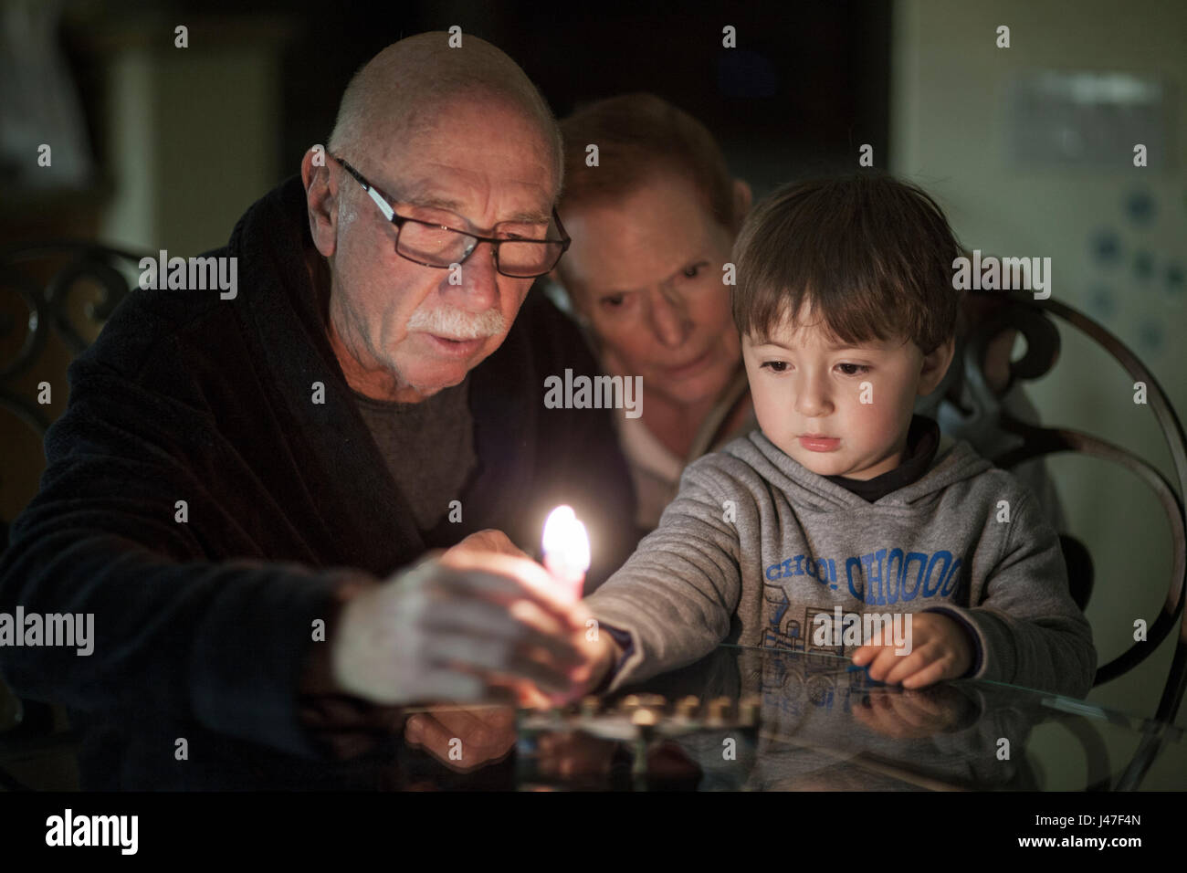 Famiglia ebraica di nonni e loro nipote Hanukkah illuminazione candele in un menorah per la holdiays Foto Stock