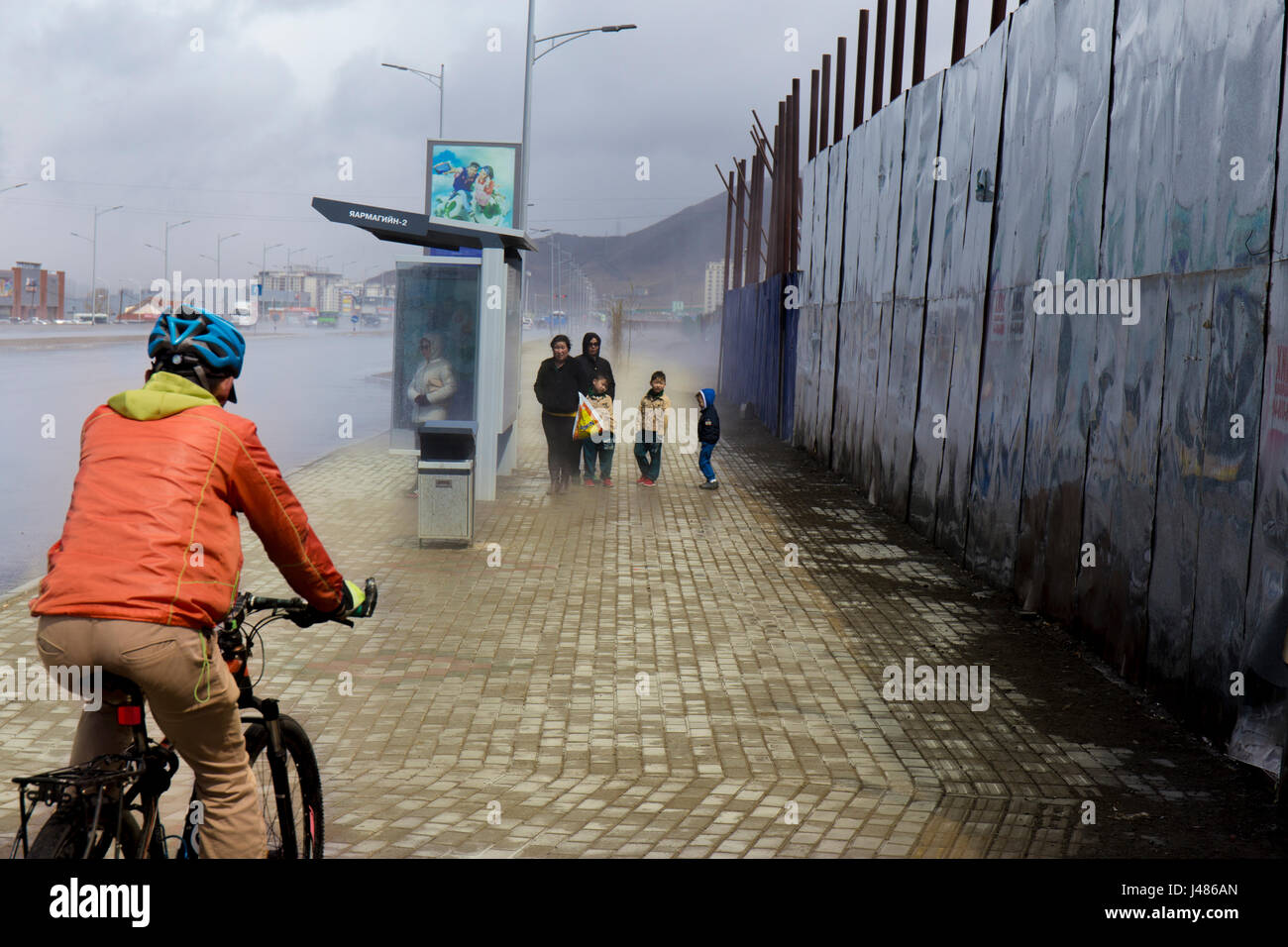 Ciclista e passeggero durante una tempesta in Ulan Bator Foto Stock