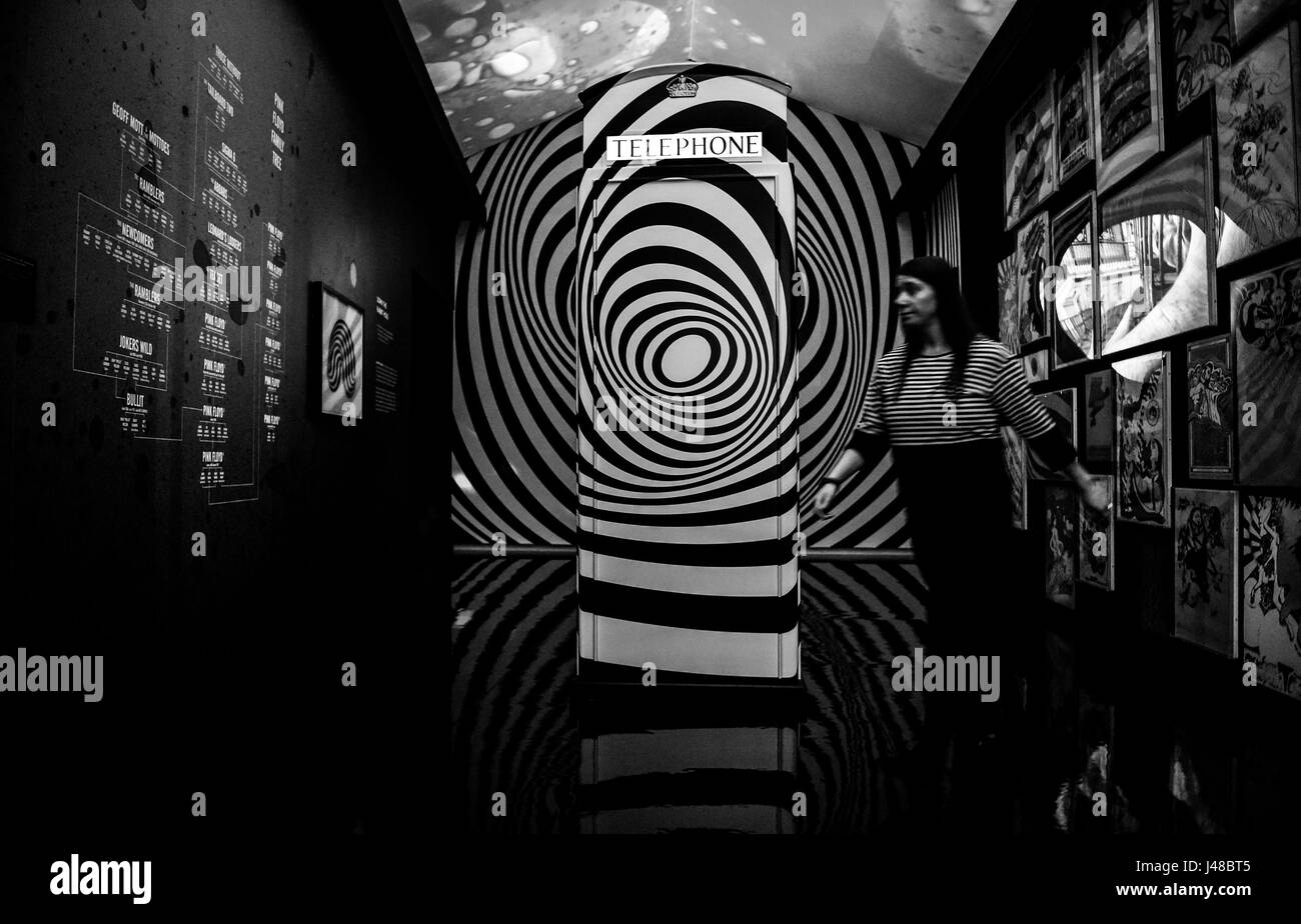 CONVERTITO IN BIANCO E NERO UN membro del personale passa davanti a una scatola telefonica in una stanza decorata con il tema della scena sotterranea londinese degli anni sessanta, quando Pink Floyd era la casa band all'UFO Club, durante una telefonata e un'anteprima per la Pink Floyd Exhibition: Il loro Mortal rimane al V&A di Londra. Foto Stock