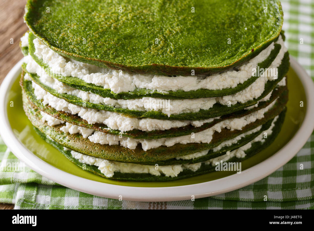 Verde torta di crepes con ricotta close-up su una piastra orizzontale. Foto Stock
